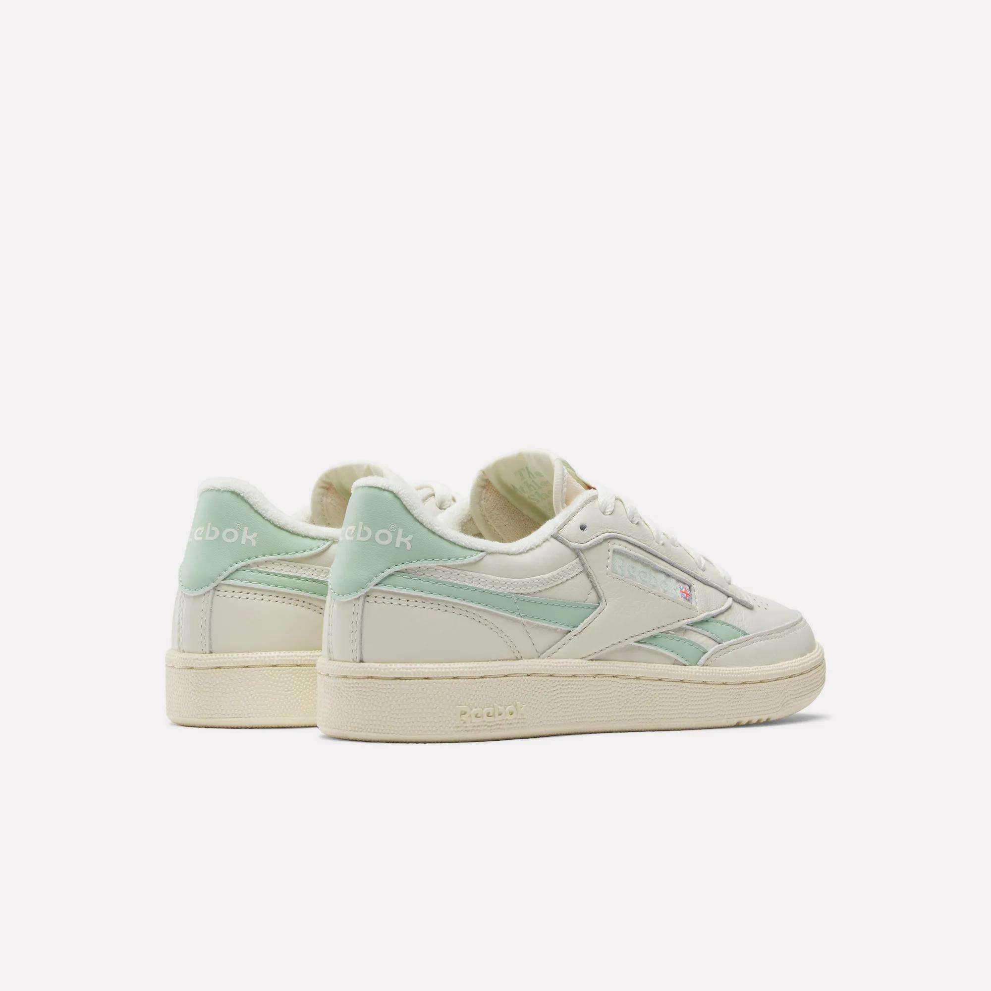 A pair of Women's Club C Revenge Vintage Shoes by Reebok in off-white with light green accents are displayed on a white background, showing both back and side views.