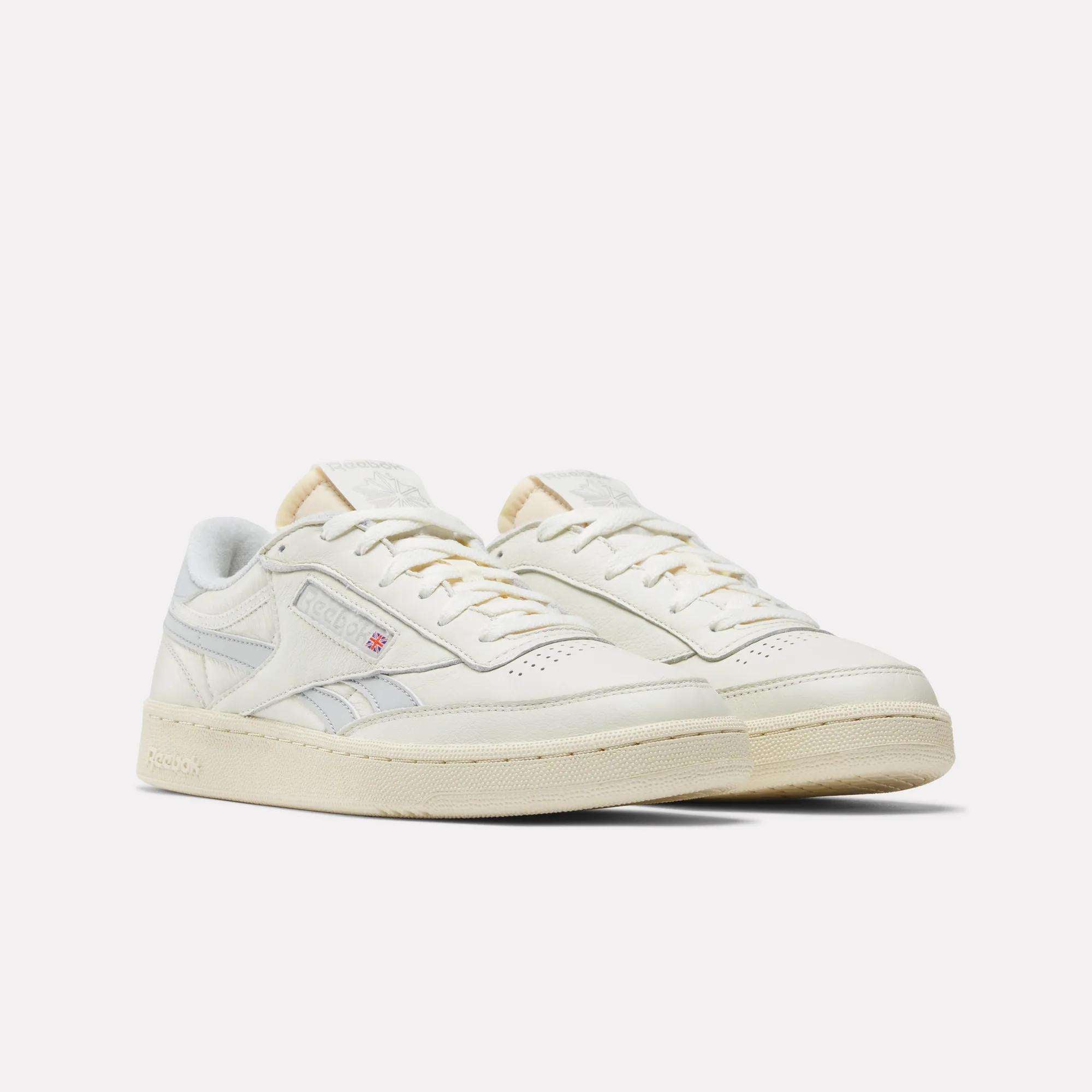 The Reebok Club C Revenge Vintage Shoes feature an off-white, full-grain leather upper, cream colored soles, light blue side logo accents, and a low-cut design. Displayed on a plain white background.