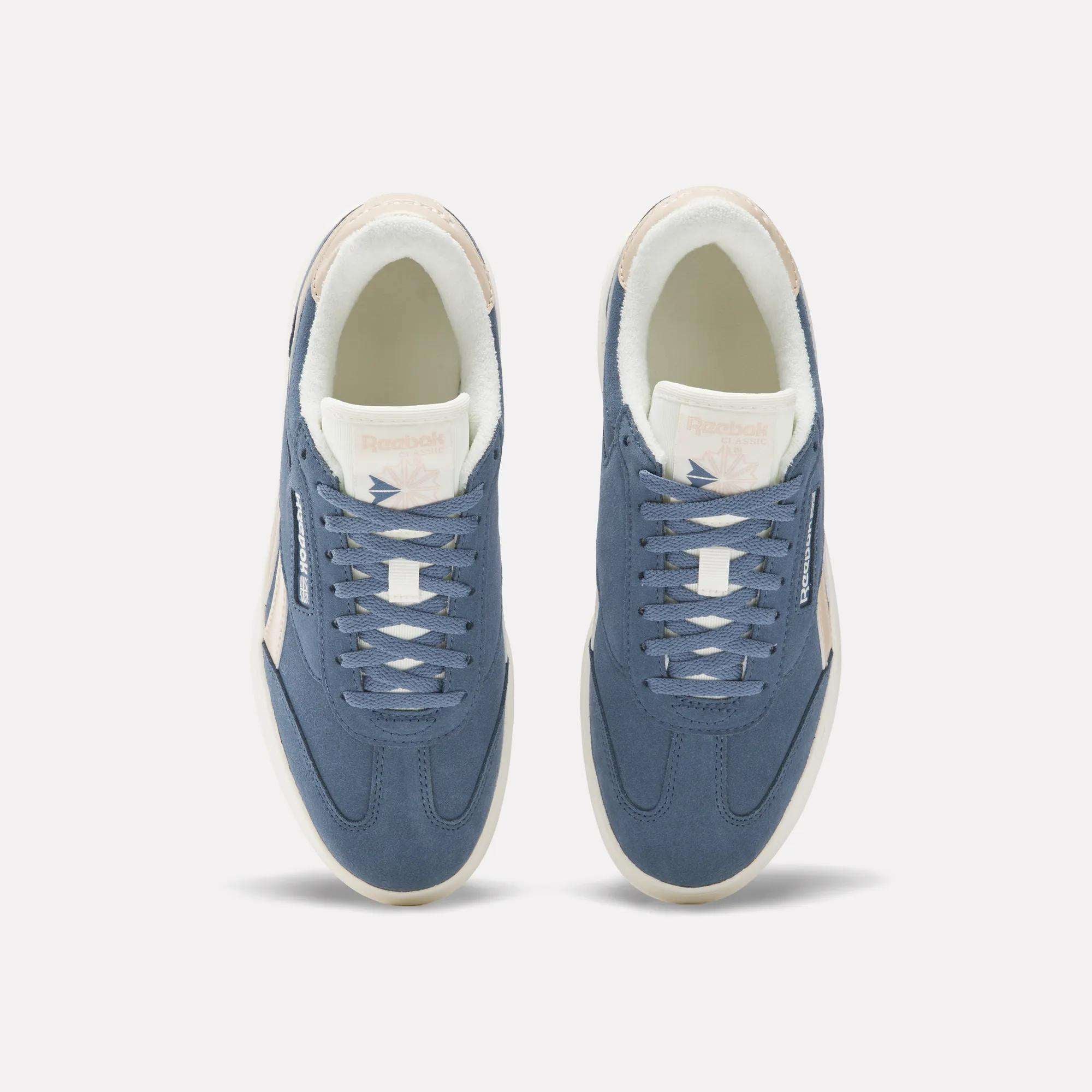 A pair of Campio Extra Women's Shoes by Reebok in blue suede are shown from above, with white laces, off-white soles, and light pink Reebok branding on the tongue and side, set against a plain white background.