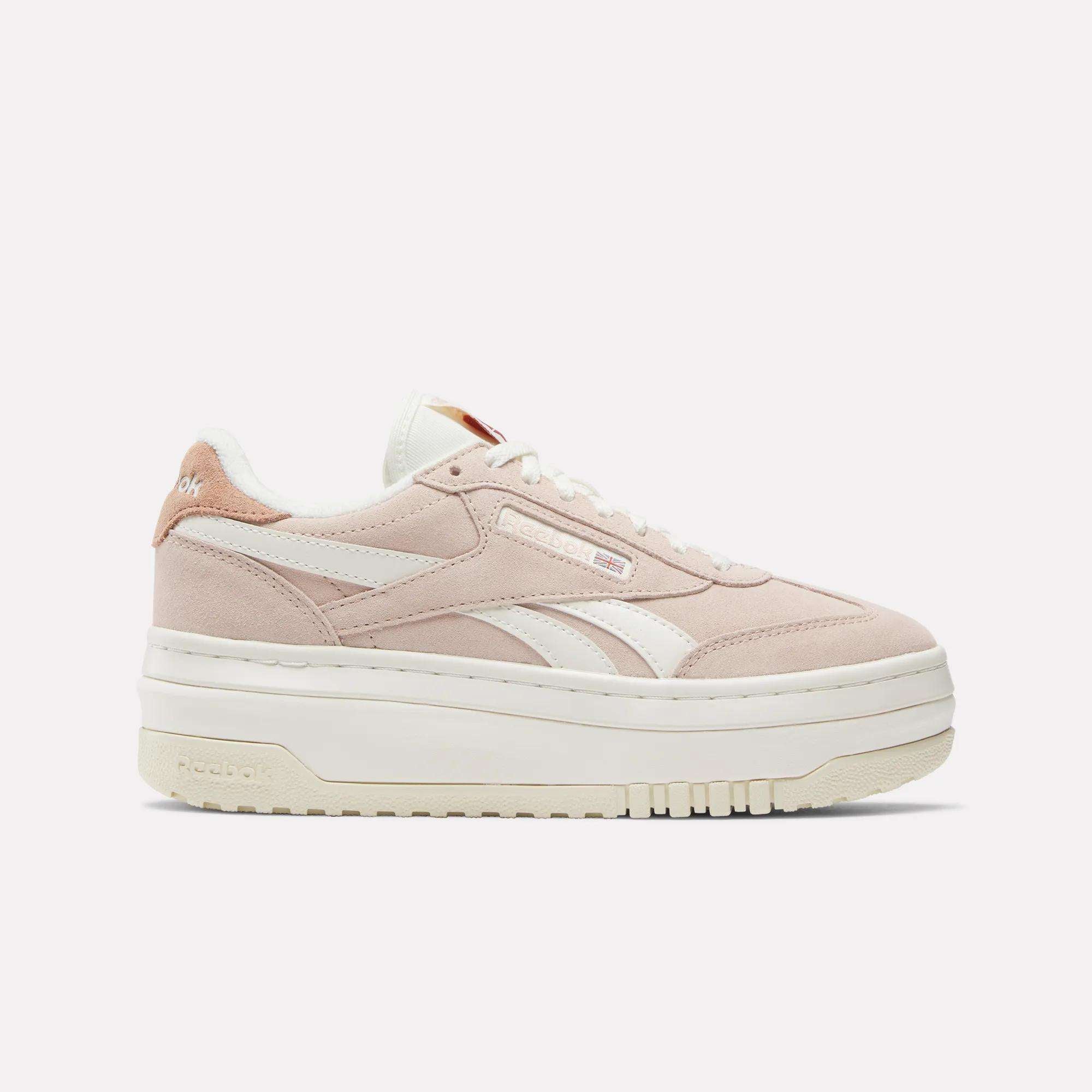 The Women's Campio Extra Shoes by Reebok feature a light pink chunky design with white accents, suede platform details, white laces, and a thick sole. The Reebok logo is visible on the side and heel against a plain white background.