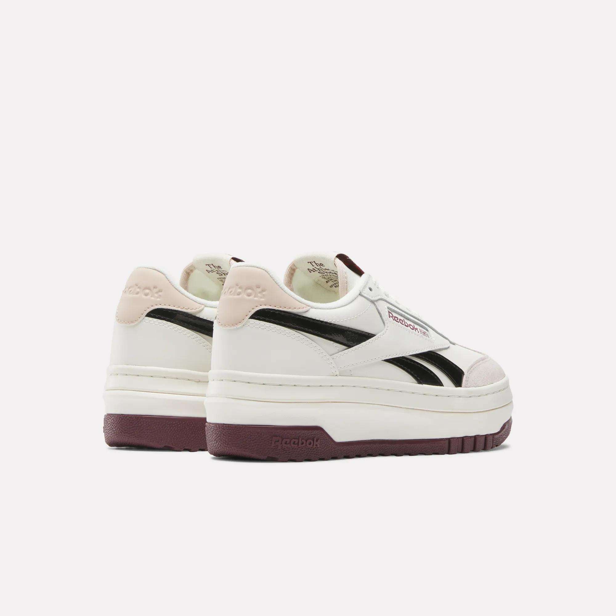 A pair of Women's Campio Extra Shoes by Reebok, featuring a leather upper, black side stripes, maroon platform soles, and light pink heel accents, shown against a plain white background.
