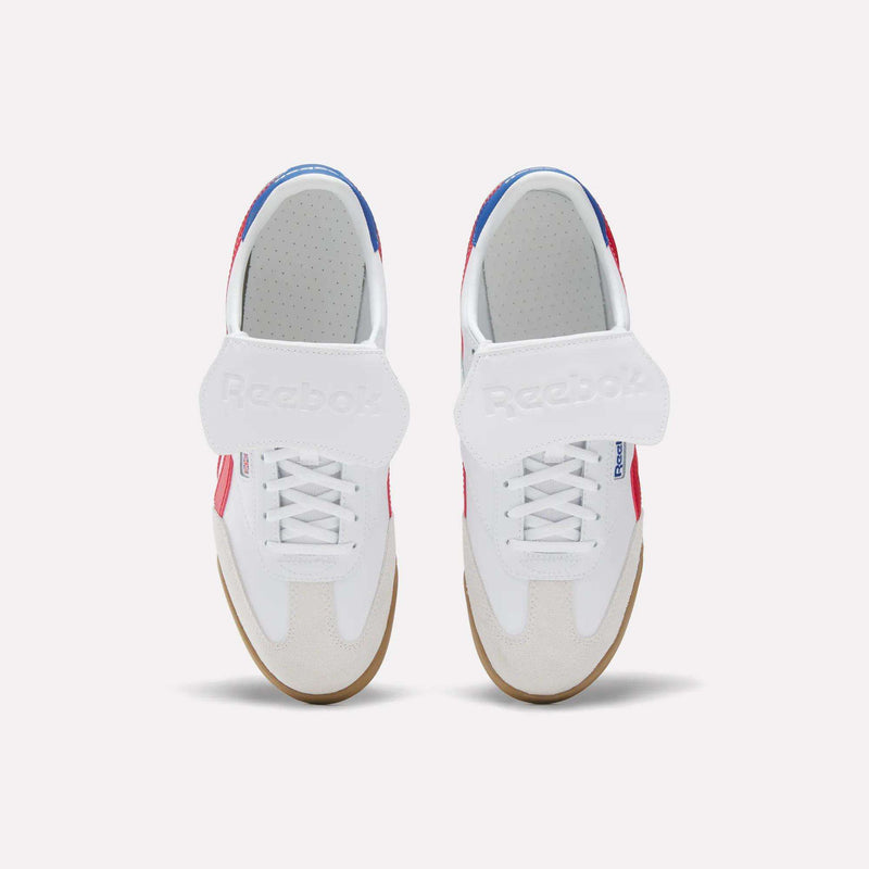 Top view of Reebok Campio XT Kilty Shoes: white tennis-inspired design with velcro straps, beige toe caps, gum soles, and red and blue accents on sides and heel, set against a plain light background.
