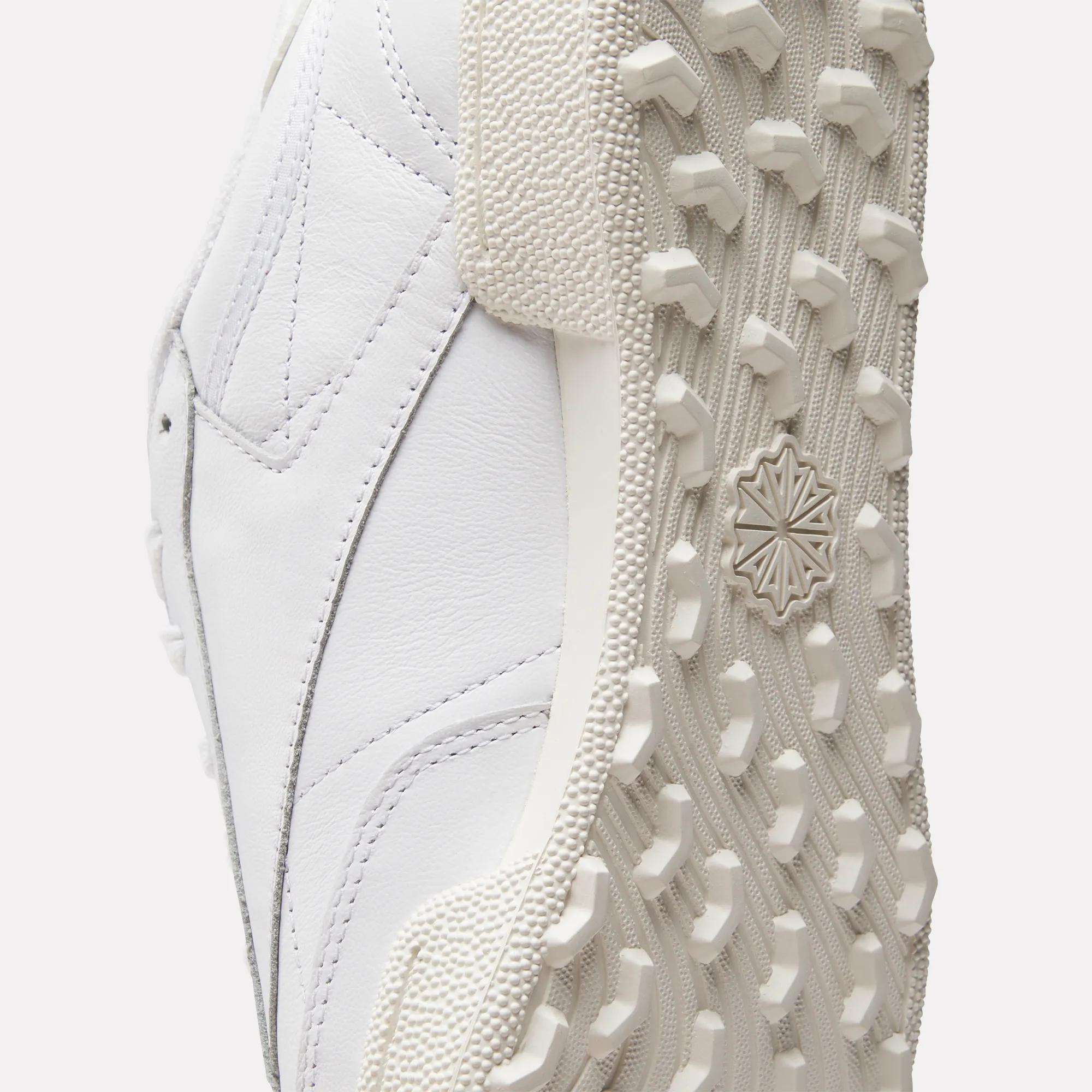 Close-up of the Reebok Men's Club C Golf Shoes shows a spikeless outsole with detailed tread and textured rubber, plus stitching and paneling on the water-resistant leather upper.