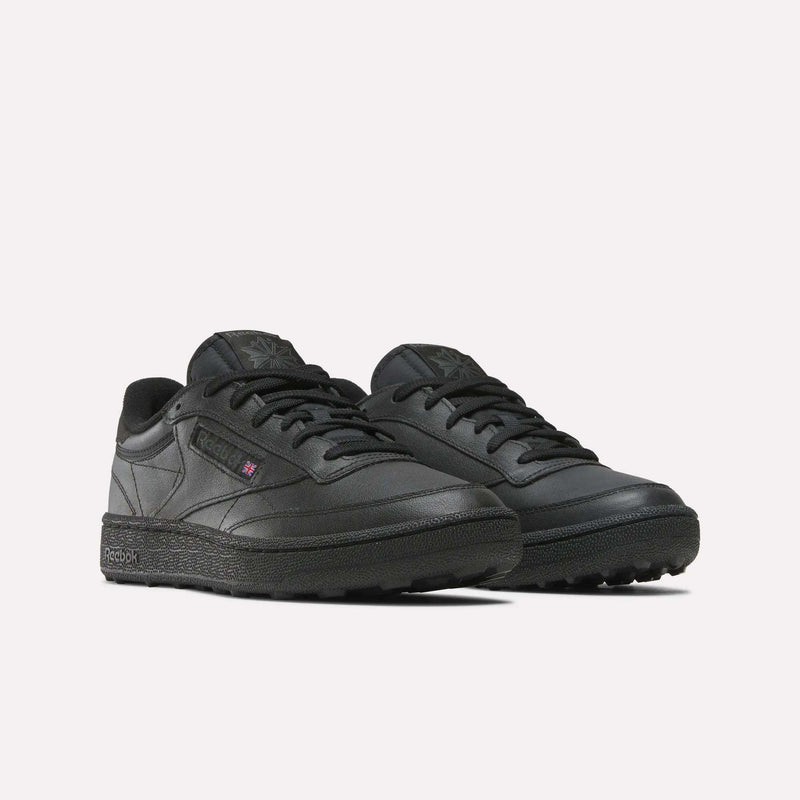 The Reebok Men's Club C Golf Shoes feature a black low-top design with a spikeless, textured outsole and subtle branding on the side, tongue, and heel, shown against a plain white background.
