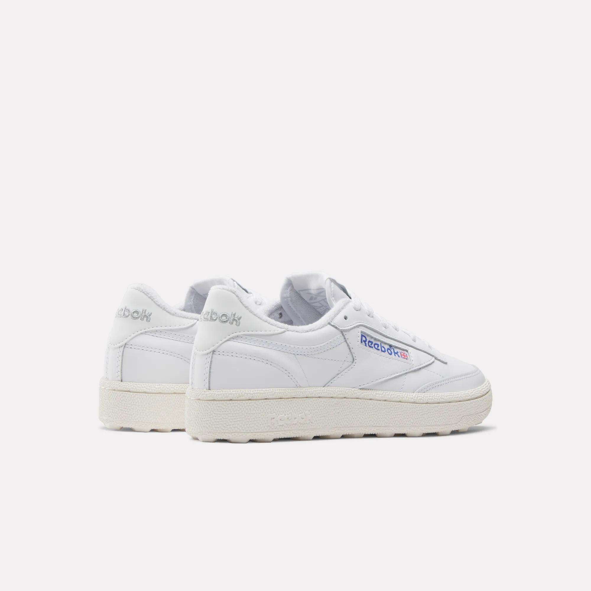 The Women's Club C Golf Shoes by Reebok are classic white sneakers with off-white soles and a spikeless outsole, featuring the Reebok logo on the side and heel. They are photographed against a plain white background.