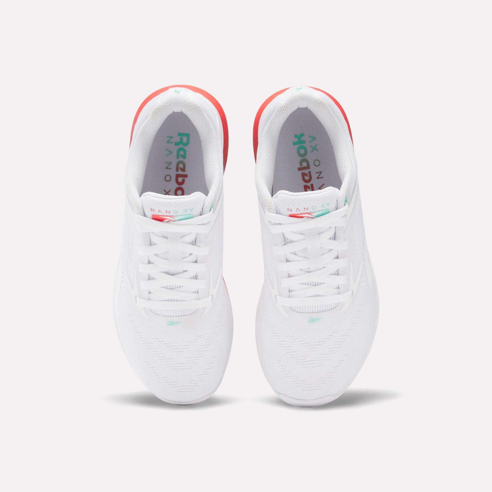 A pair of Reebok Women's Nano X5 Training Shoes in white, seen from above, with white laces, subtle teal accents, and a hint of red on the heels for comfort.