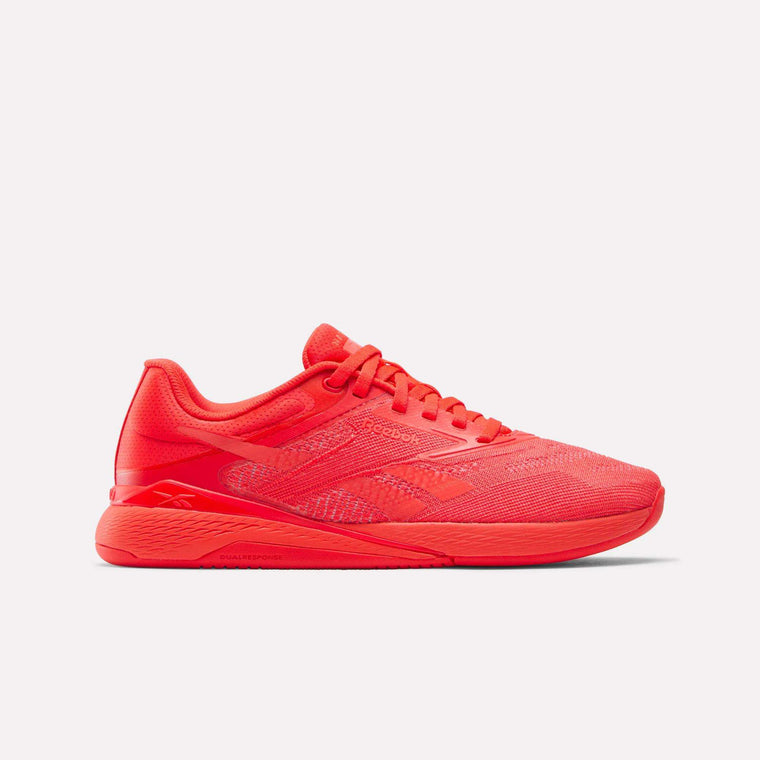 The Reebok Women's Nano X5 Training Shoes, in bright red with mesh fabric, synthetic overlays, lace-up closure, and textured rubber sole, are shown in a side view on a white background—ideal for women’s shoe collections.