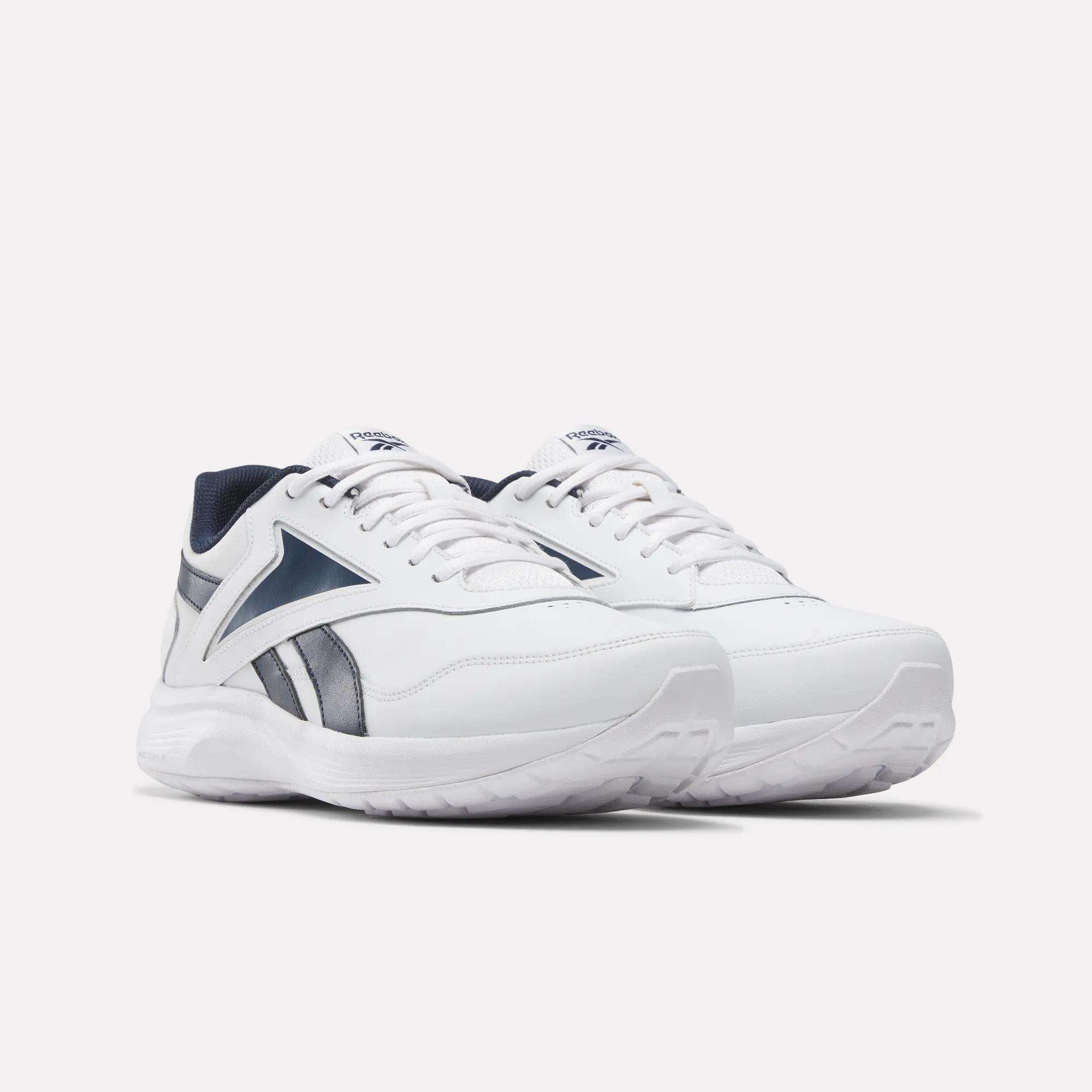 A pair of Reebok Men's Walk Ultra 7 DMX Max Wide 4E Shoes in white with navy accents and laces, featuring air cushioning, a chunky sole, and a sporty wide-fit design for extra comfort. Shown on a plain light background.