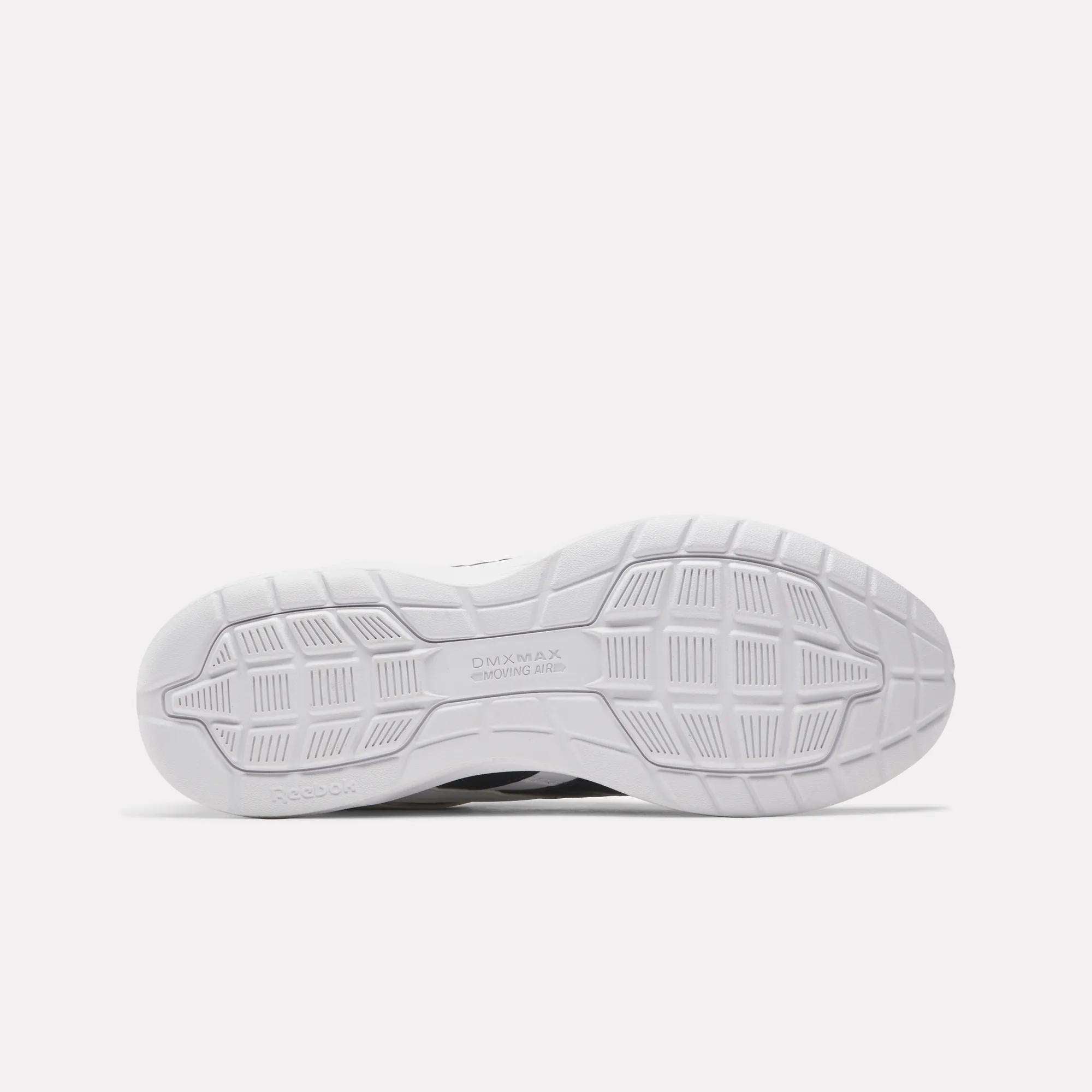 The image displays the white rubber outsole of Reebok Walk Ultra 7 DMX Max Walking Shoes, featuring a patterned tread with grooves and geometric shapes for traction. "DMX MAX" and "Reebok" are embossed, emphasizing their cushioned comfort.