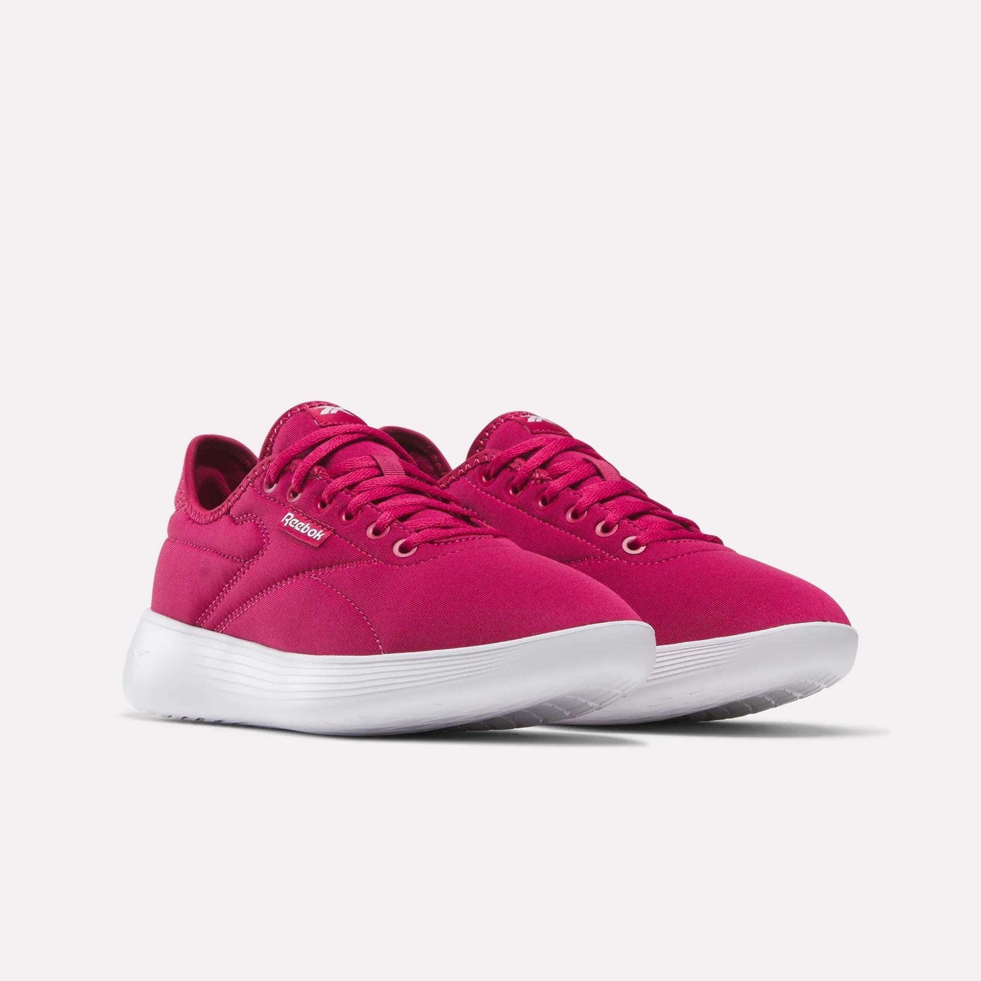 A pair of Women's Active Lite Shoes by Reebok in bright pink with white soles, featuring laces and a simple, modern design, shown at an angle on a plain light background.