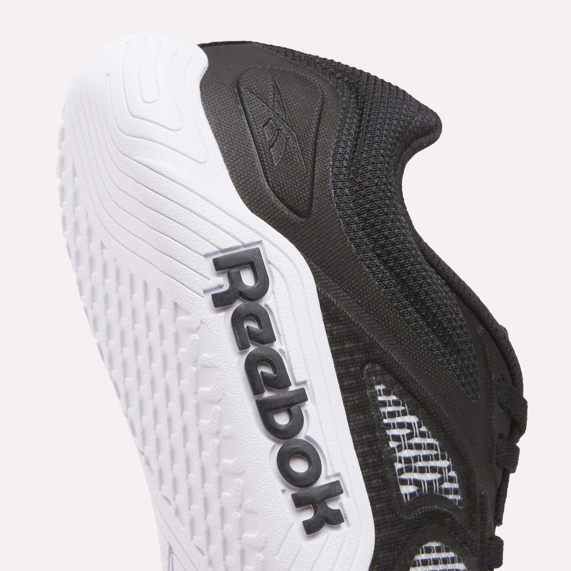 Close-up of the side and sole of Reebok Women's Nano Zero Training Shoes in black and white, with a textured white outsole and bold black Reebok logo—perfect for strength training.