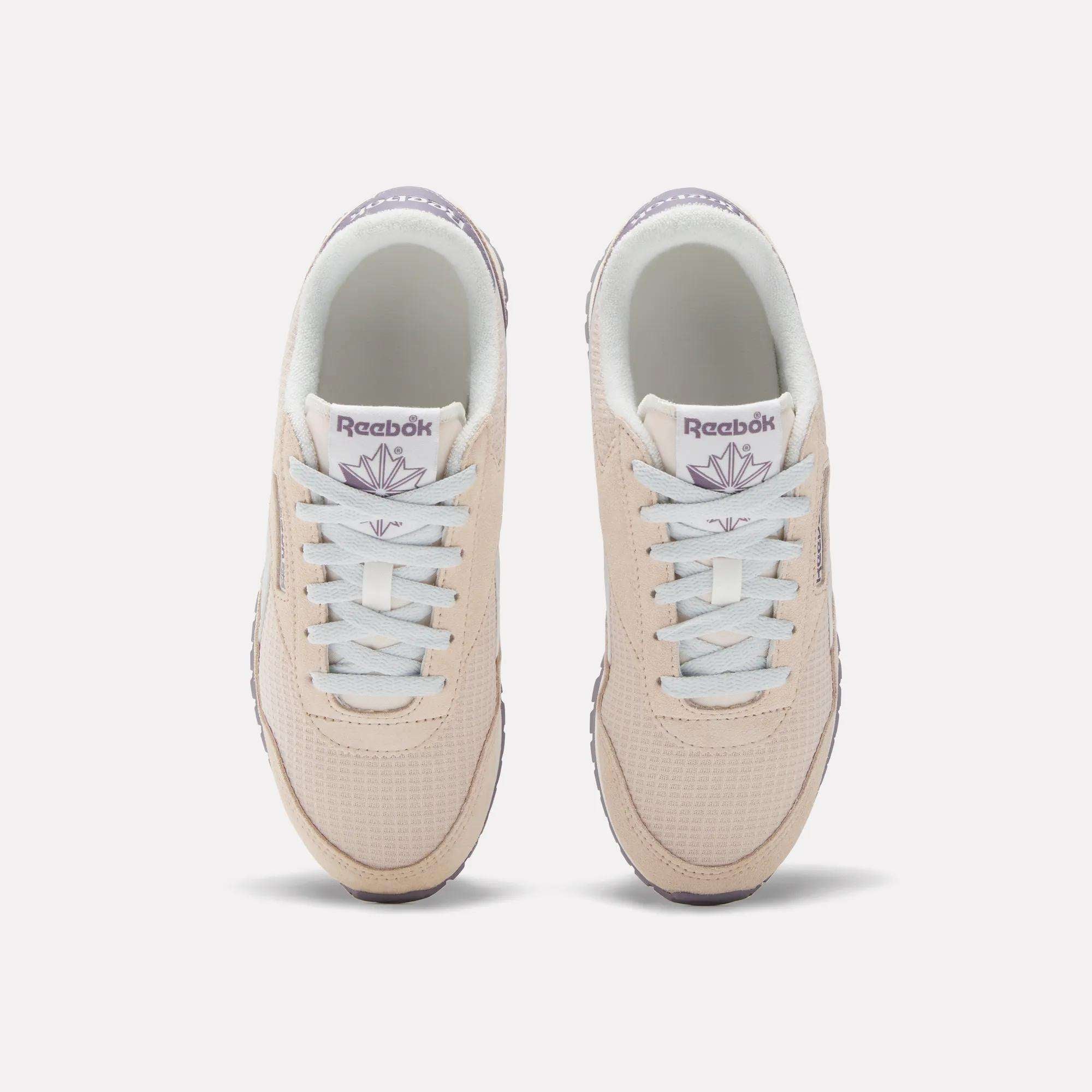 The Women's Classic AZ Shoes by Reebok are beige with white laces and light purple branding, shown from above on a white background—ideal for fans of 70s-style sneakers.