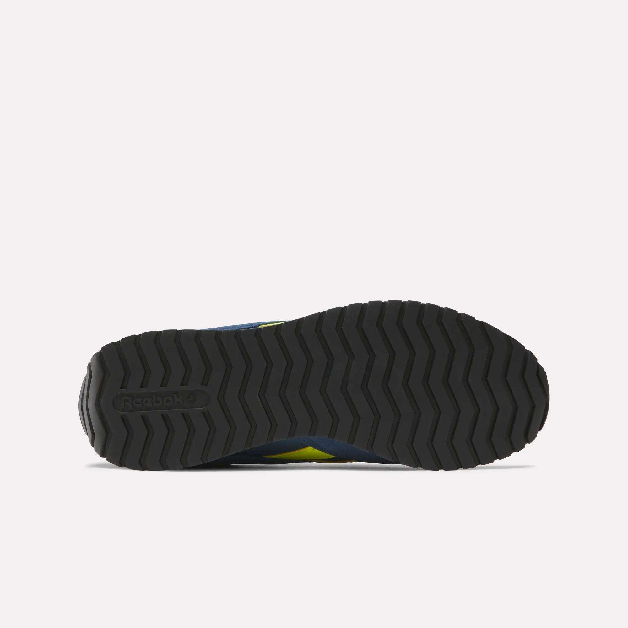 Bottom view of a black Reebok Classic AZ Shoes outsole, showing a zigzag tread inspired by '70s retro running shoes and the embossed Reebok logo on the heel, all set against a plain white background.
