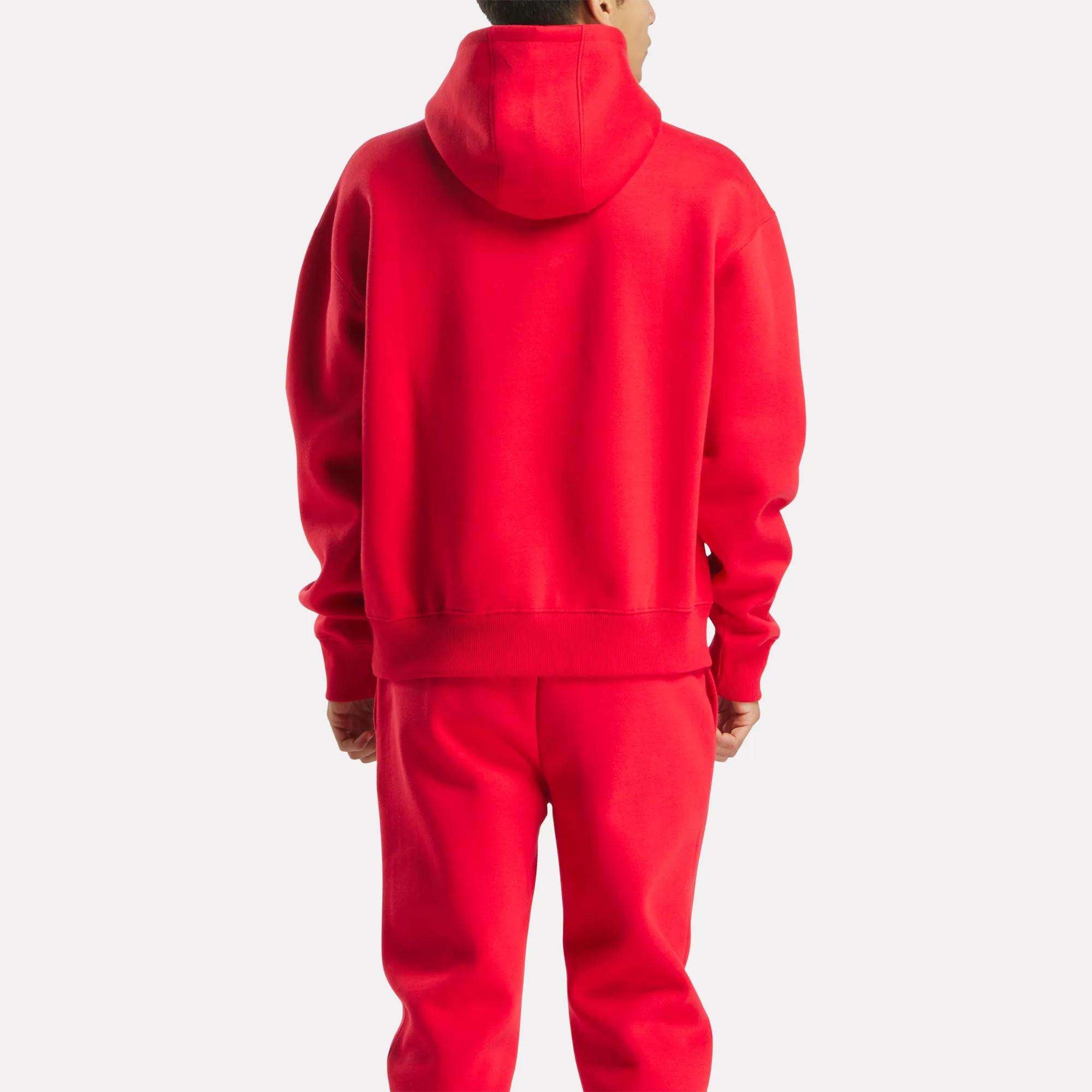 A person faces away from the camera, wearing a bright red Reebok Men's Hoodie and matching red sweatpants against a plain light background.
