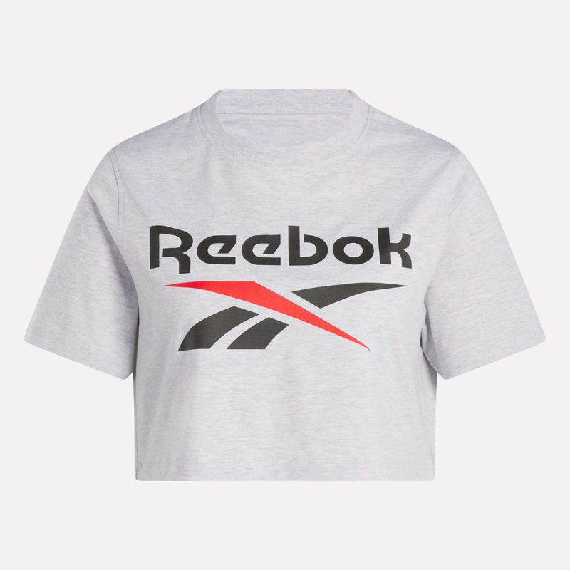 The Women's Two-Color Logo Crew Cropped Short Sleeve Tee by Reebok features a bold black Reebok logo and name with a striking red and black graphic below, on light gray fabric, displayed against a plain white background.