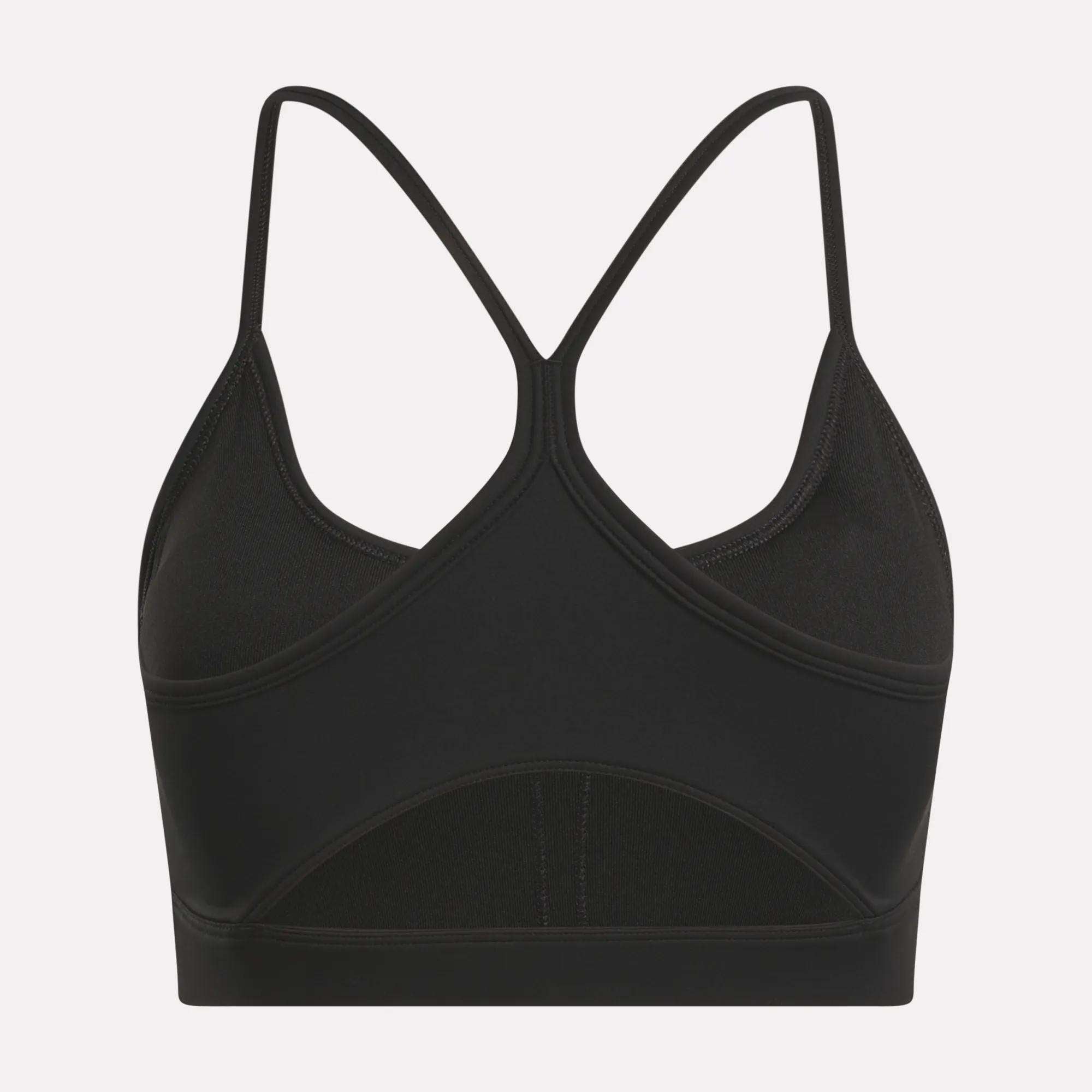 The Reebok Women's Core Strappy Bra offers medium support with thin, crisscrossed racerback straps and a seamless black design—ideal for workouts. Displayed on a plain white background.