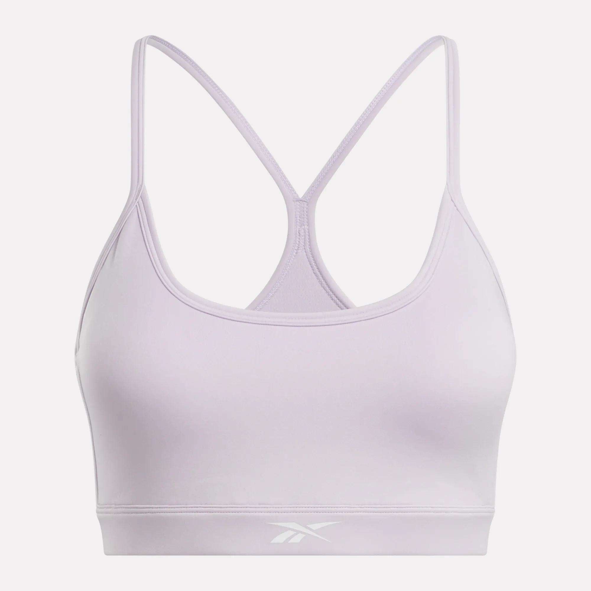 The Reebok Women's Core Strappy Bra offers medium support for workouts, featuring thin racerback straps, a scoop neckline, and the Reebok logo on the front band in light lavender.