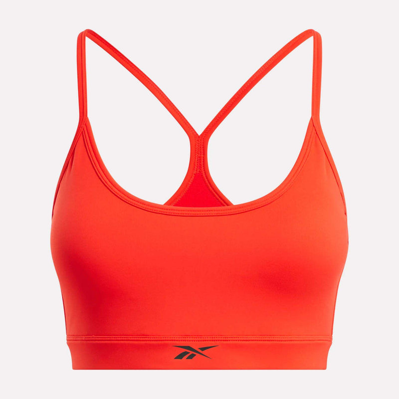 The Reebok Women's Core Strappy Bra - Medium Support features thin adjustable straps and a racerback, ideal for medium-impact workouts. It’s bright orange with a black Reebok logo on the front band, shown on a plain white background.