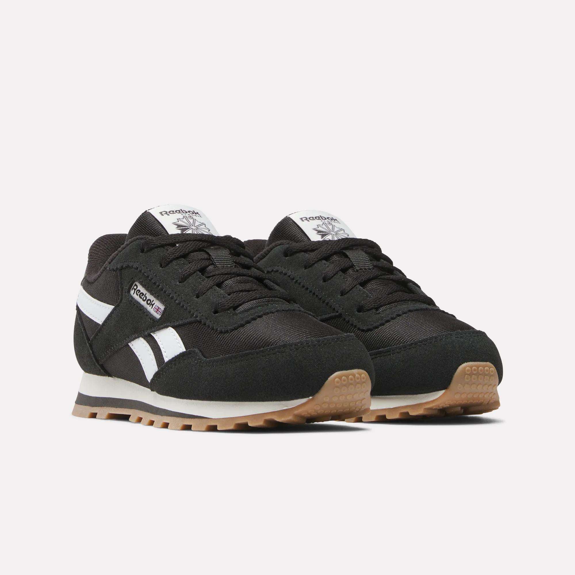 A pair of Reebok Classic AZ Shoes for little kids in black with white accents, foam cushioning, white side stripes, gum rubber soles, and the Reebok logo on the side and tongue, shown on a plain light background.