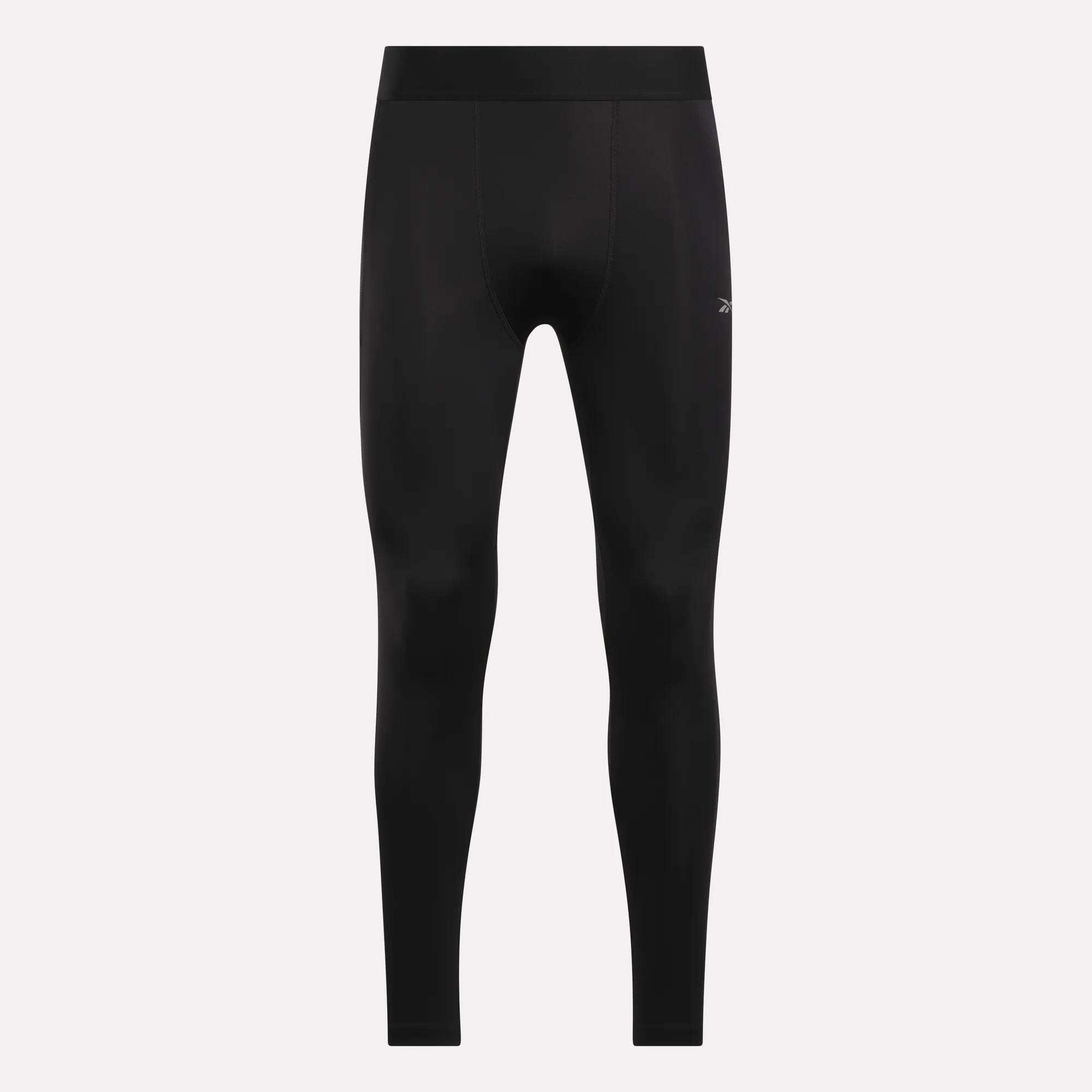 The Men's Core Training Tights by Reebok are black, fitted workout tights with a small left-thigh logo, high waistband, and sweat-wicking fabric, shown against a light background.