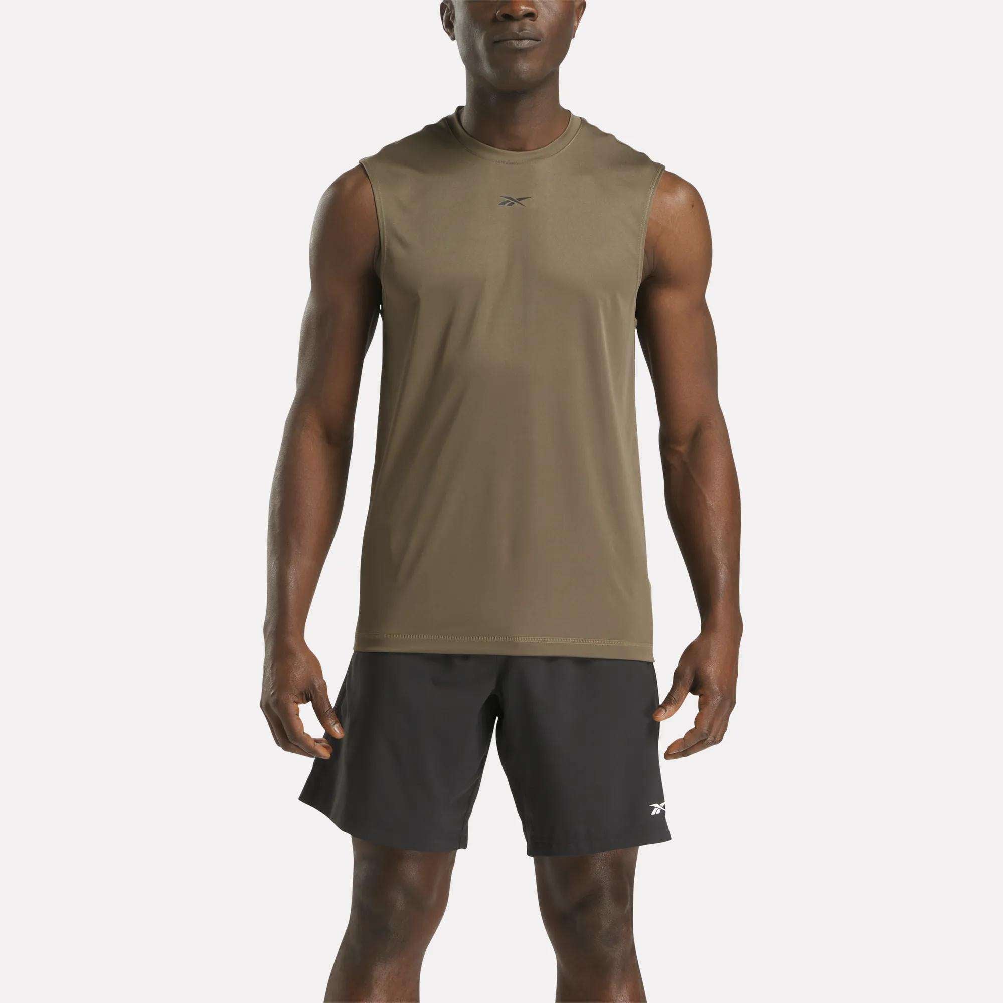 A man faces forward against a white background wearing the Reebok Men's Train Sleeveless Tech Tee in olive green with black shorts. The lightweight polyester jersey ensures comfort and breathability for workouts.