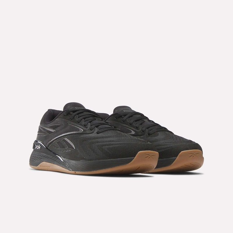 A pair of black Reebok athletic sneakers with brown rubber soles, shown at an angle on a plain light background.