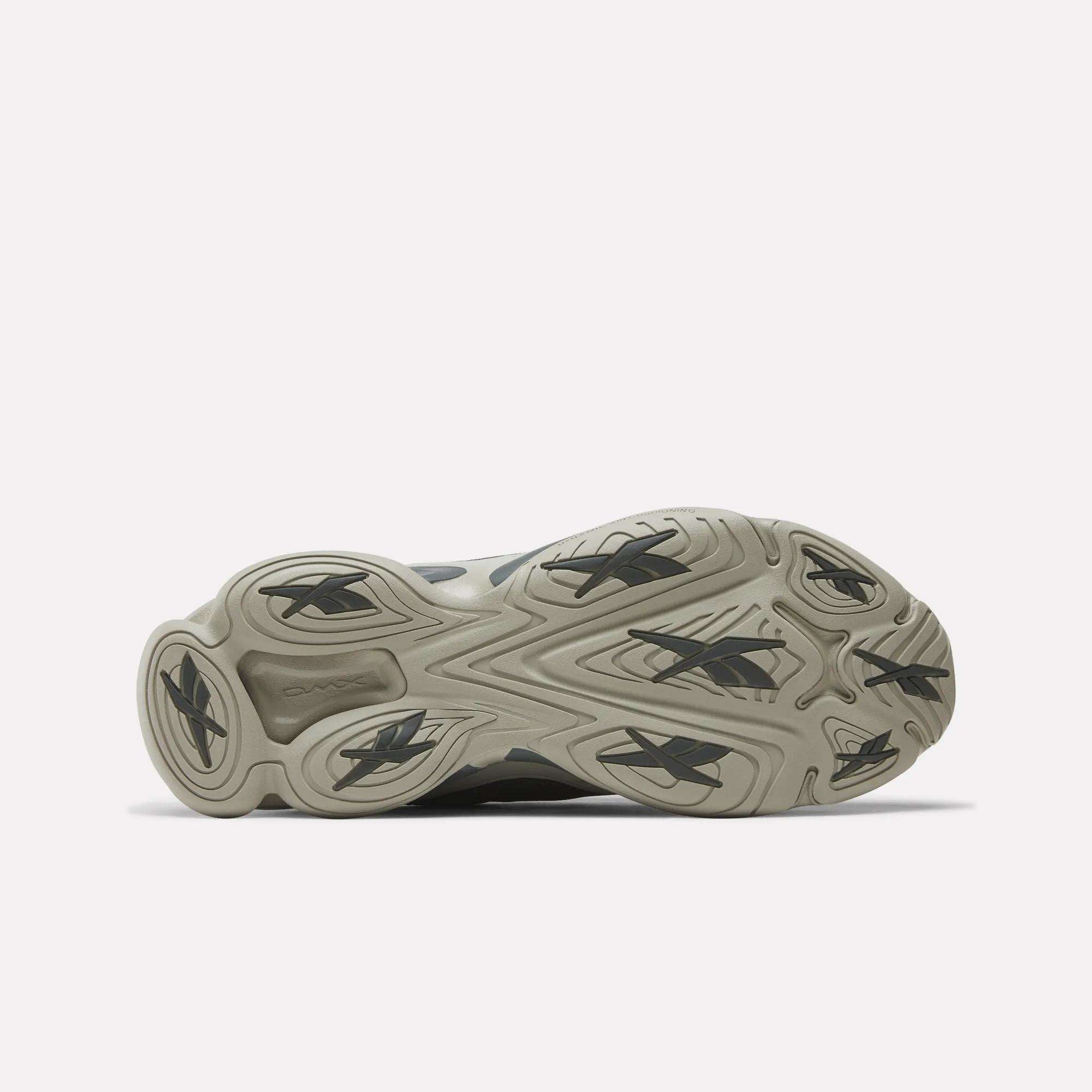 Bottom view of Reebok DMX Series 3000 Shoes with a light gray rubber outsole, multiple black Reebok logos, and a wavy tread pattern for traction and comfort, highlighting the brand’s innovative design.