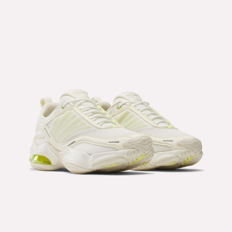A pair of Reebok Women's DMX Series 3000 Training Shoes in off-white with mesh and synthetic overlays, chunky DMX 3 cushioned soles, and light yellow accents on the sides, soles, and heels, displayed on a plain white background.