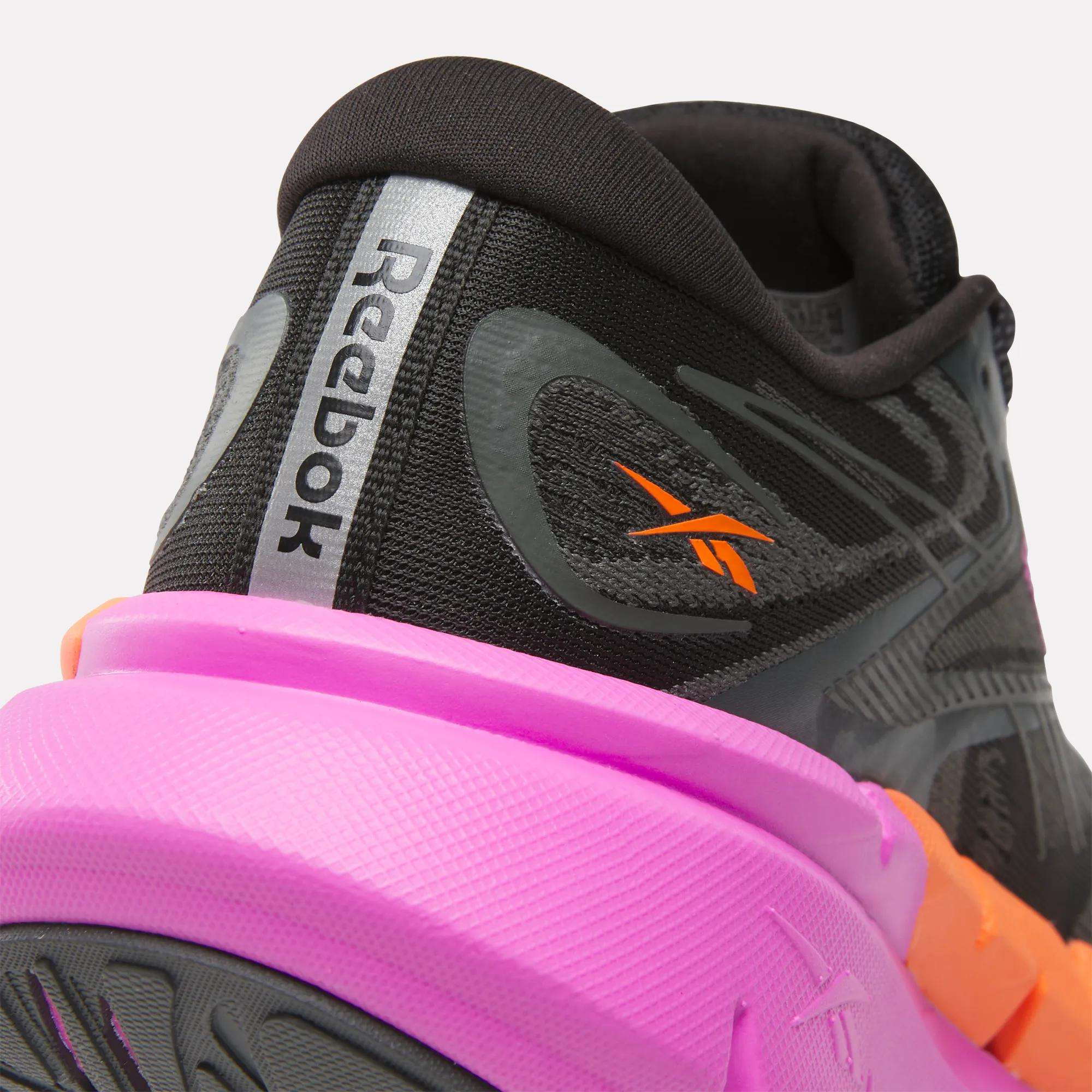 Close-up of the heel of Reebok Women's FloatZig Double Running Shoes in black with bold pink and orange accents. The Reebok logo highlights the cushioned design, built for comfort on max-cushioned miles.