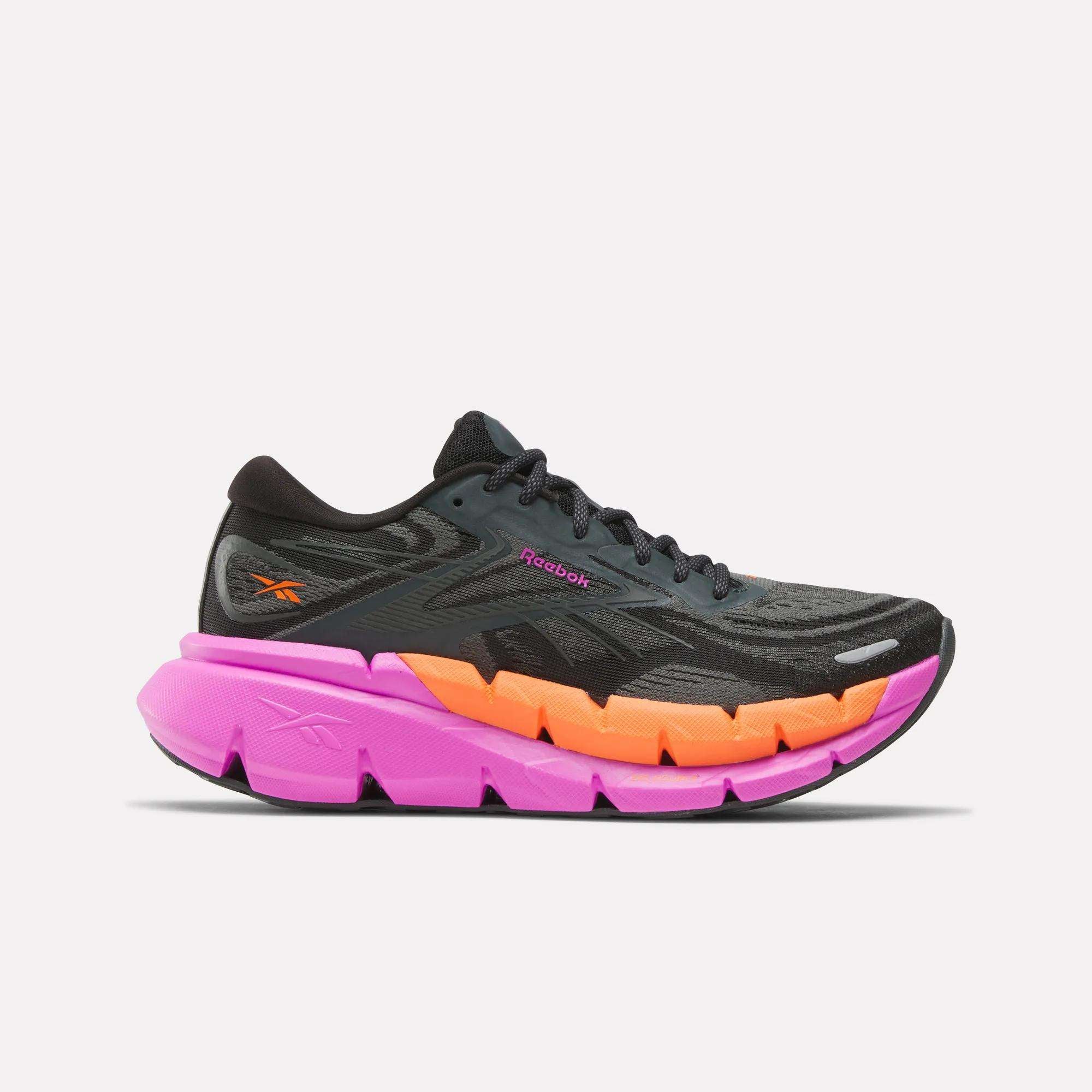 The Reebok Women's FloatZig Double Running Shoes feature a black and gray mesh upper with orange and pink accents, plus a thick vibrant pink-orange sole—delivering max-cushioning for comfortable runs.