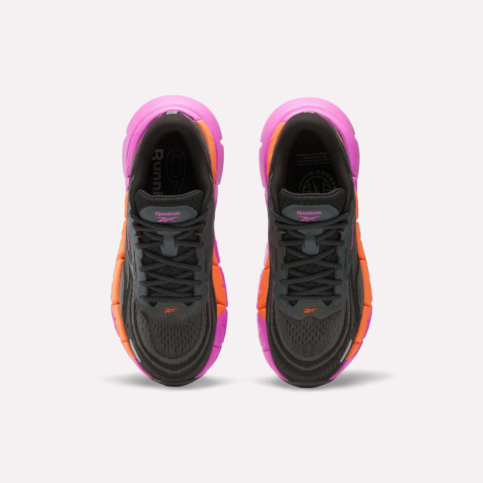 Top-down view of Reebok Women's FloatZig Double Running Shoes in black with orange and pink soles and accents, placed side by side on a plain white background—ideal max-cushion sneakers for comfortable runs.
