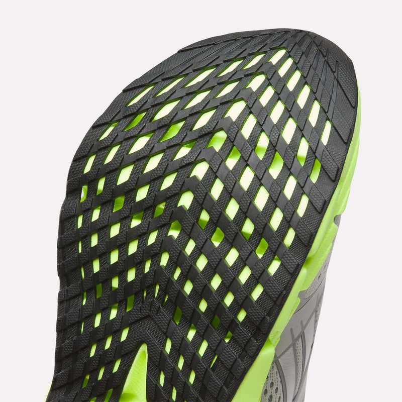Close-up of the sole on Reebok Women's FloatZig 2 Running Shoes, showcasing a unique black grid tread over neon green with Superfloat+ cushioning; part of the gray upper is also visible.