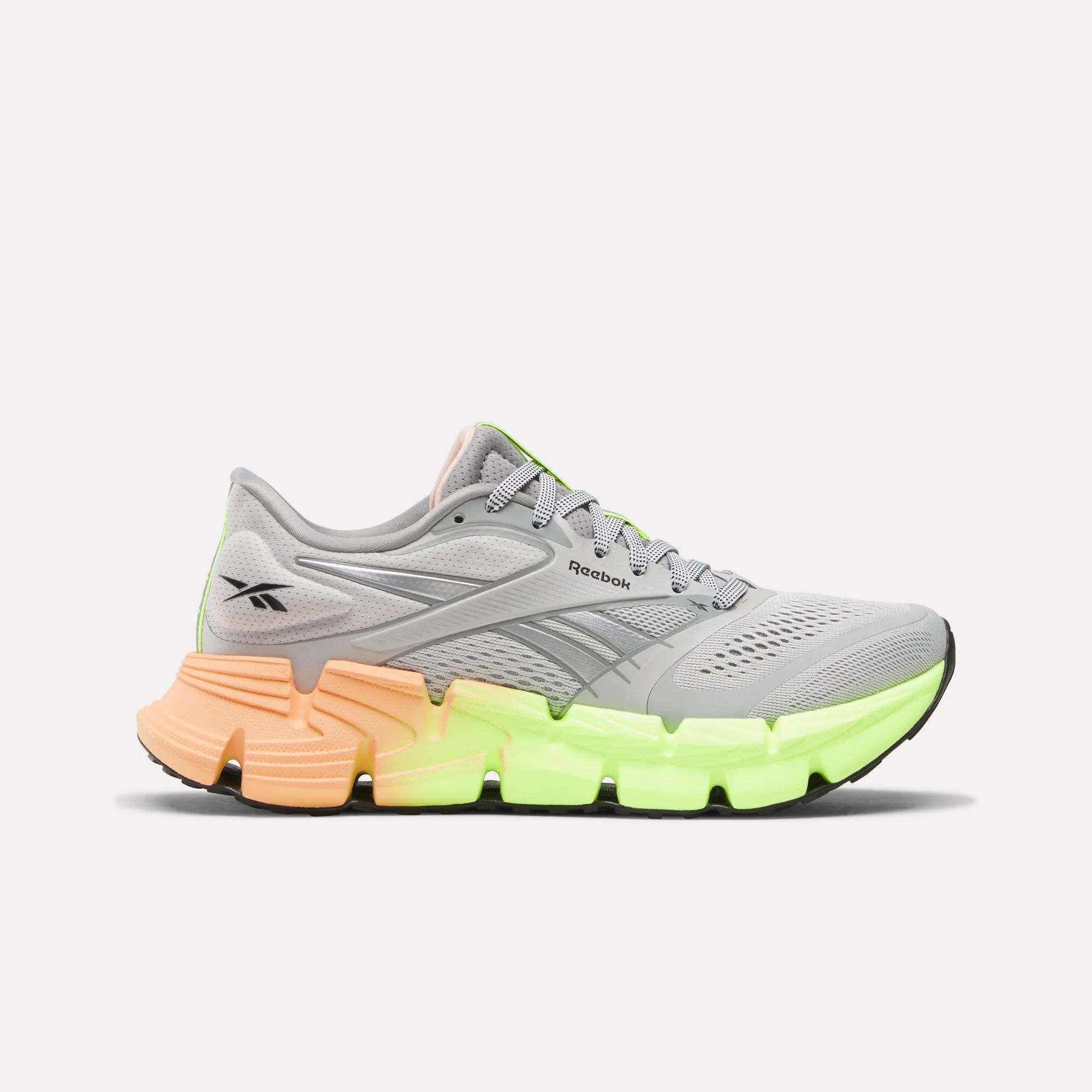 The Reebok Women's FloatZig 2 Running Shoes feature a gray mesh upper, Superfloat+ cushioning, a neon green front sole, and an orange heel—delivering comfort and style, shown on a plain white background.