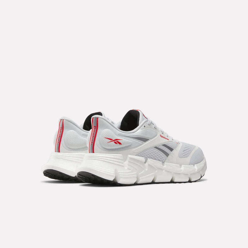 A pair of Reebok Men's FloatZig 2 Running Shoes in white with red and gray details, showcasing energy-returning cushioning, displayed from the back and side on a plain light background.