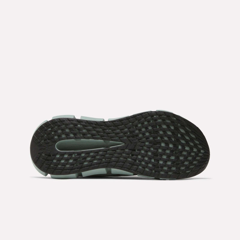The image displays the black, textured sole of Reebok Men's FloatZig 2 Running Shoes, featuring a grid-like tread and central groove photographed from below on a white background to enhance traction and support Superfloat+ cushioning.
