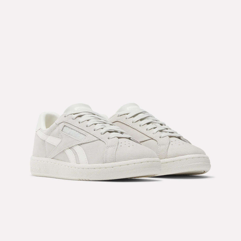 A pair of Women's Club C Grounds UK Shoes by Reebok in light grey suede with white accents and textured soles, shown against a plain white background.