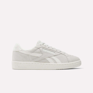 The Reebok Women's Club C Grounds UK Shoes feature light grey suede, white laces, a white outsole, and side branding. Photographed on a plain white background, they're perfect for elevating your women's footwear collection.