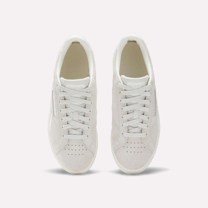 A pair of Women's Club C Grounds UK Shoes by Reebok, shown from above with visible laces and perforated toe on a plain light background—a timeless choice for women’s footwear.