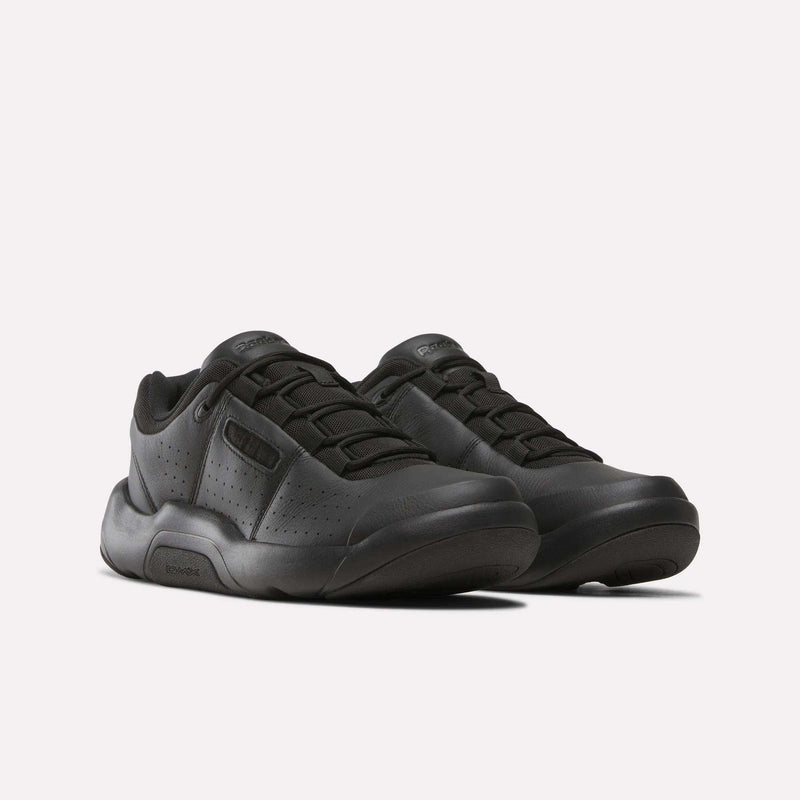 A pair of Reebok Dmx Comfort + Classic black athletic sneakers featuring perforated sides, thick rubber soles with dynamic air cushioning, and black laces, positioned side by side on a plain white background.