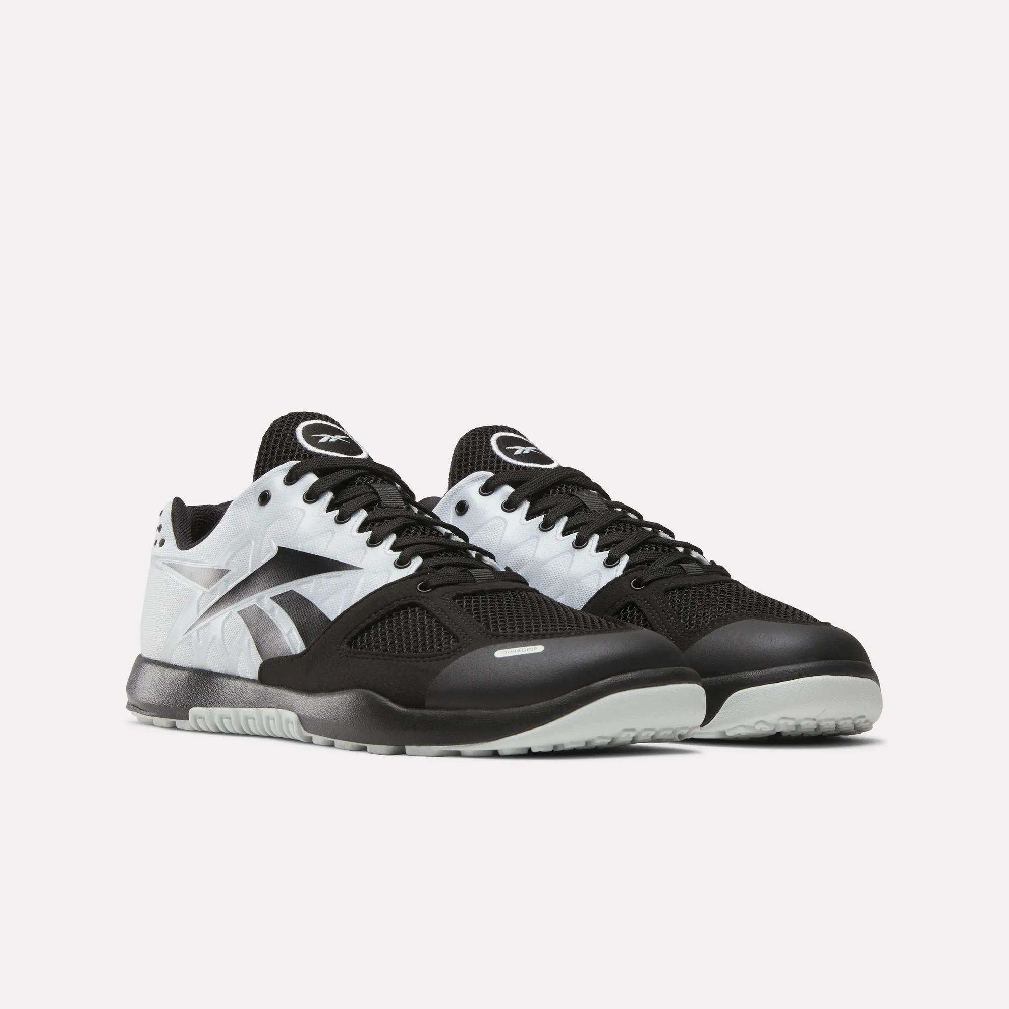 The Men's Nano 2.0 Training Shoes by Reebok feature black and white mesh uppers, black laces, white Reebok logos, and light gray soles—ideal for functional fitness—shown against a plain light background.