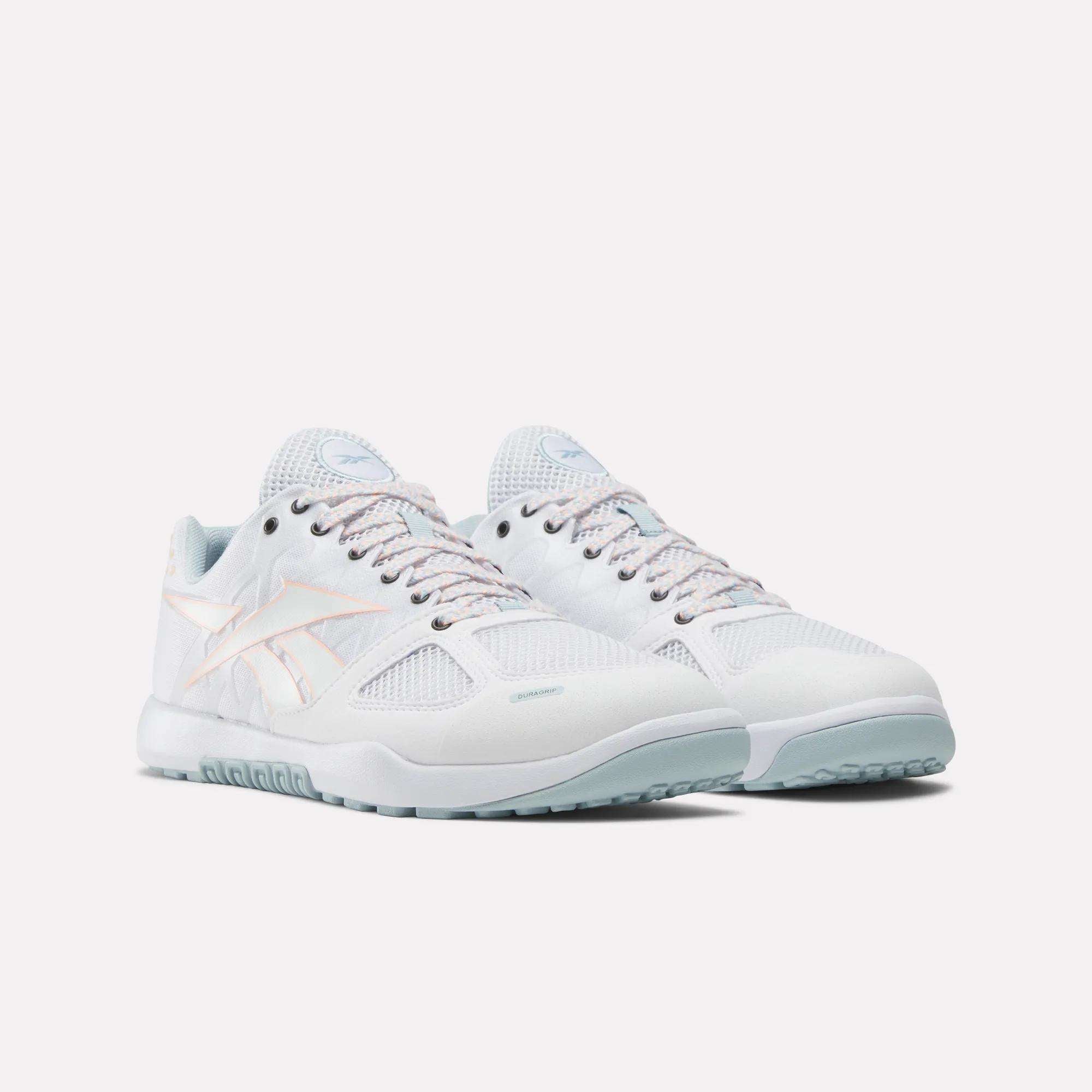 The Reebok Men's Nano 2.0 Training Shoes, in white with light blue soles and pastel pink accents, are designed for functional fitness and shown against a plain white background.