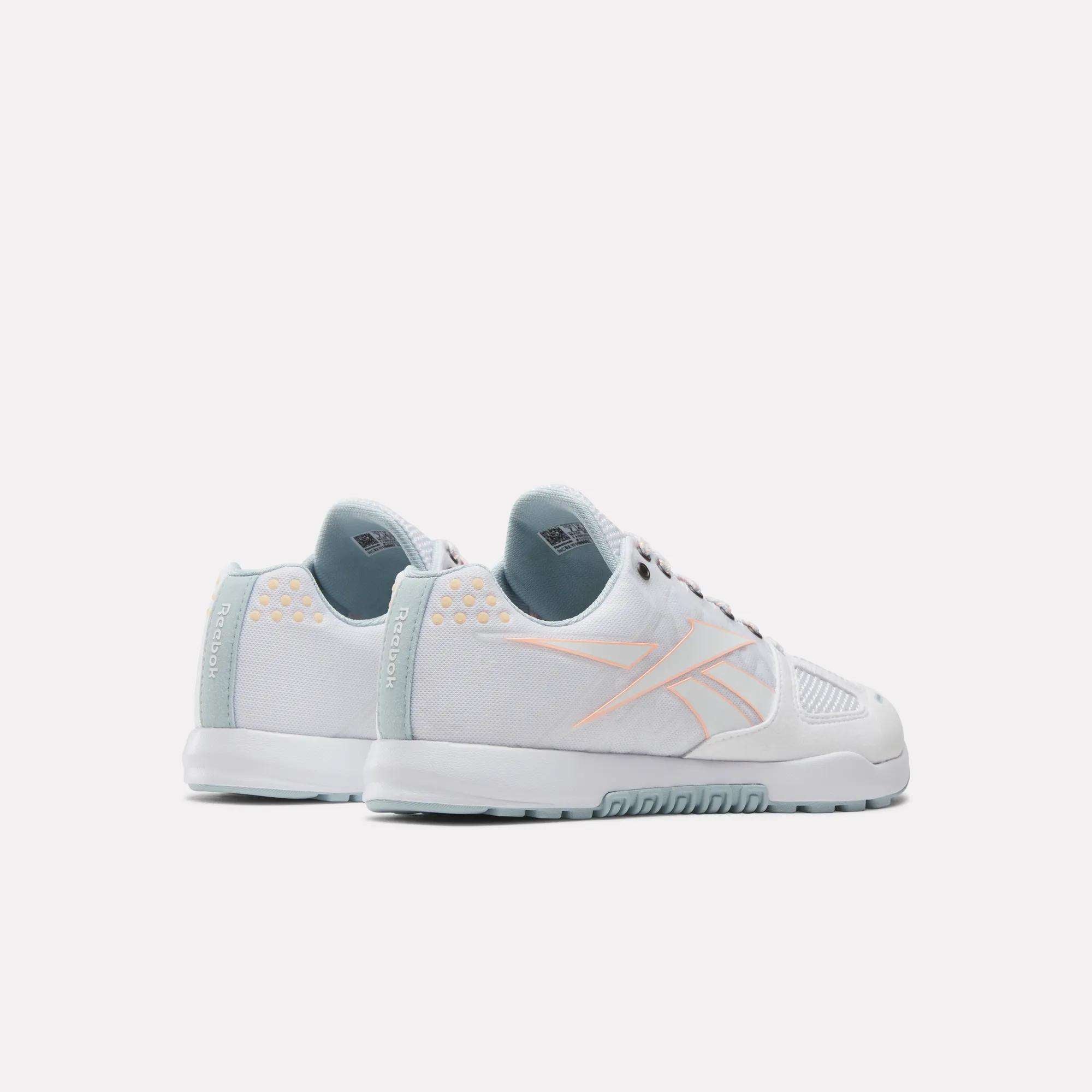 Women's Reebok Nano 2.0 Training Shoes in white with light blue soles and pink accents, featuring a subtle side logo—ideal for functional fitness—displayed from behind and at an angle on a plain white background.