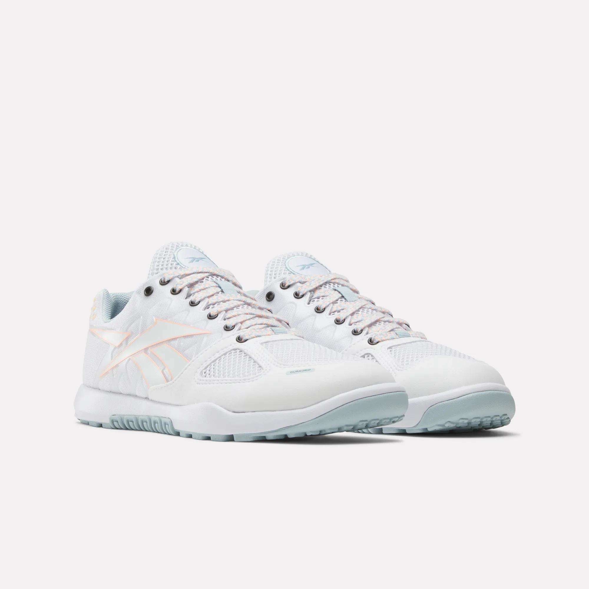 The Women's Nano 2.0 Training Shoes by Reebok feature a white design with light blue soles, pastel pink accents, and mesh panels—functional fitness sneakers shown on a plain white background.