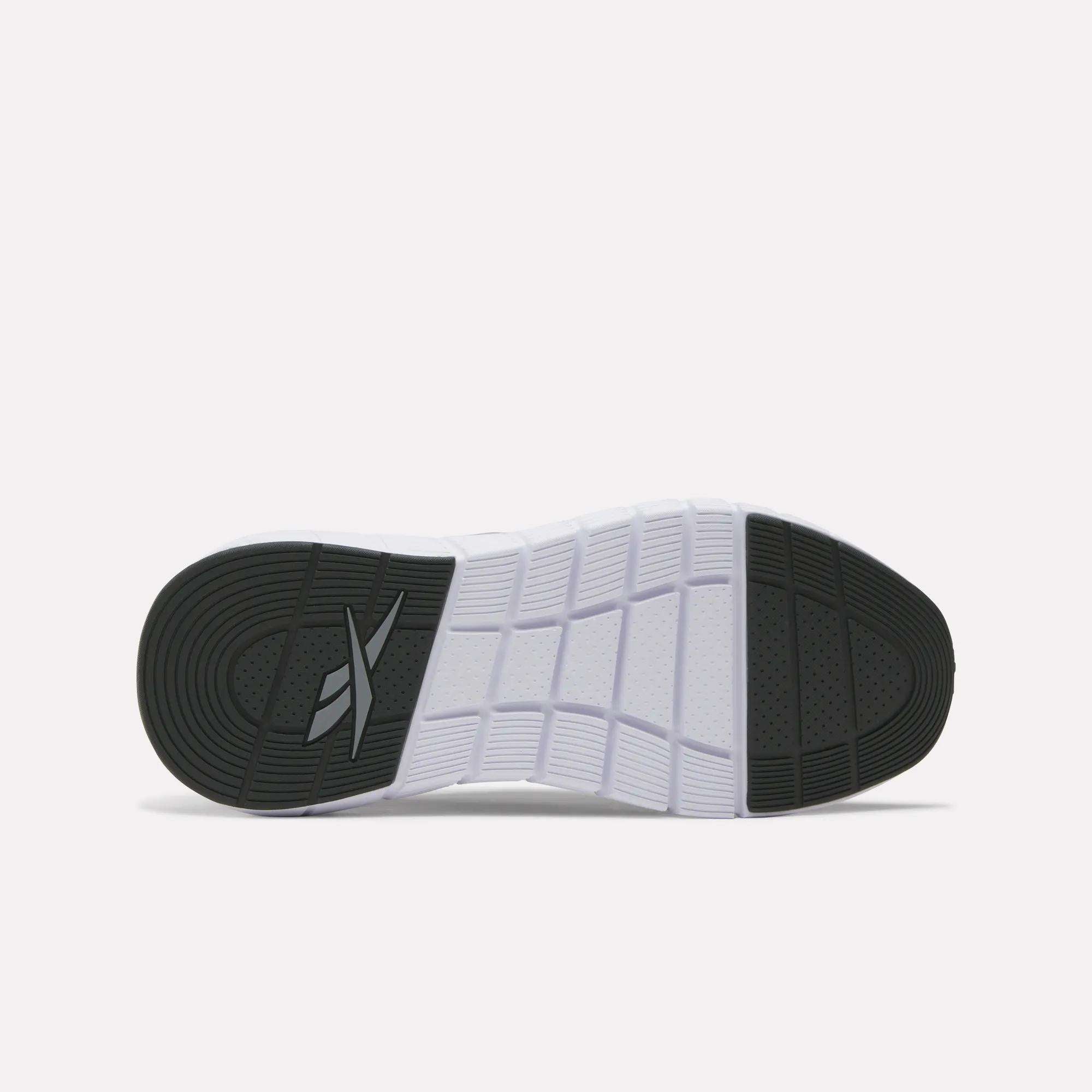 The image displays the sole of Women's Nano Gym Training Shoes by Reebok, featuring black tread at the toe and heel, a white patterned midsection, geometric grooves, and an X design for added traction—ideal for cross-training.