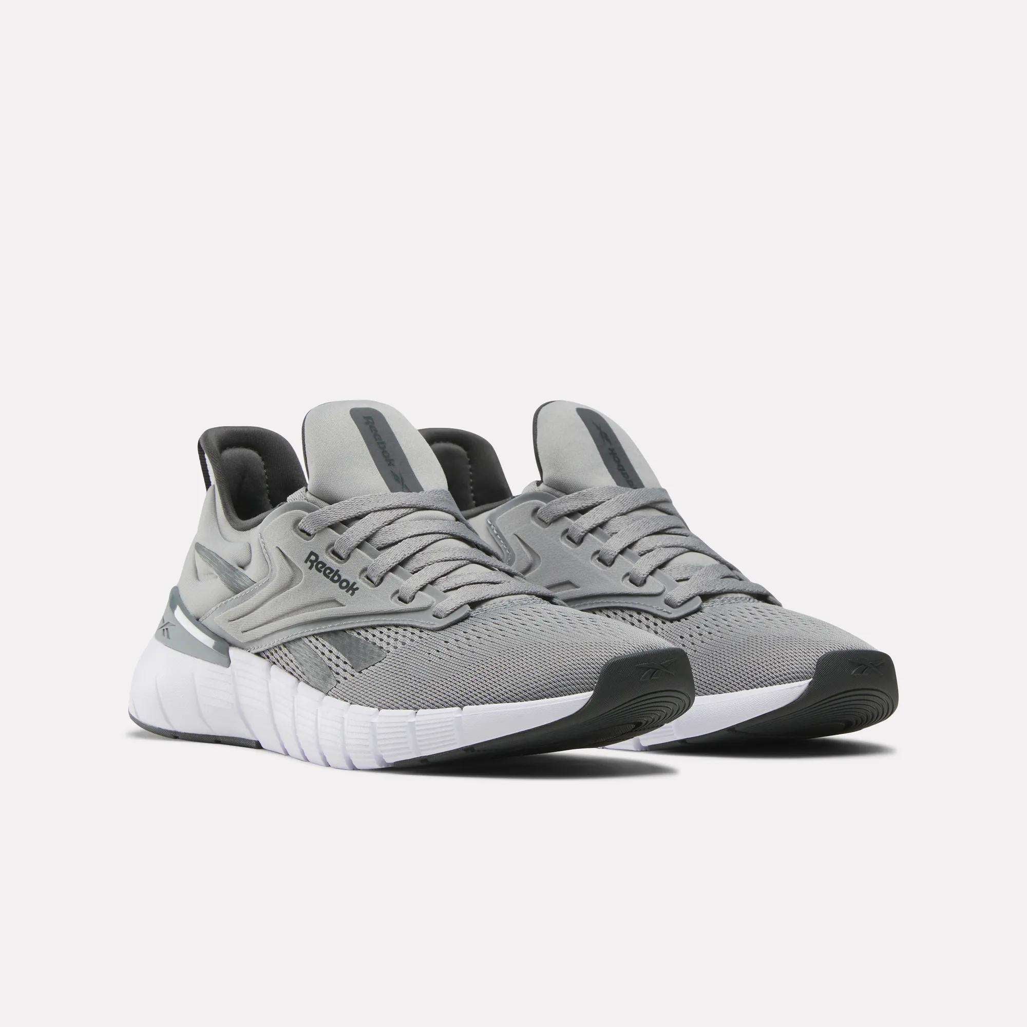 A pair of Reebok Women's Nano Gym Training Shoes in grey with white soles and black accents, showcased on a light background. These training shoes offer mesh uppers and a modern, sporty look.