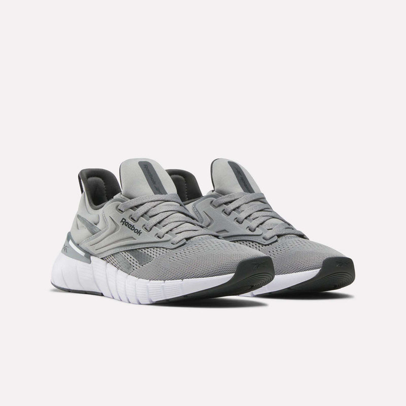 A pair of Reebok Women's Nano Gym Training Shoes in grey with white soles and black accents, showcased on a light background. These training shoes offer mesh uppers and a modern, sporty look.