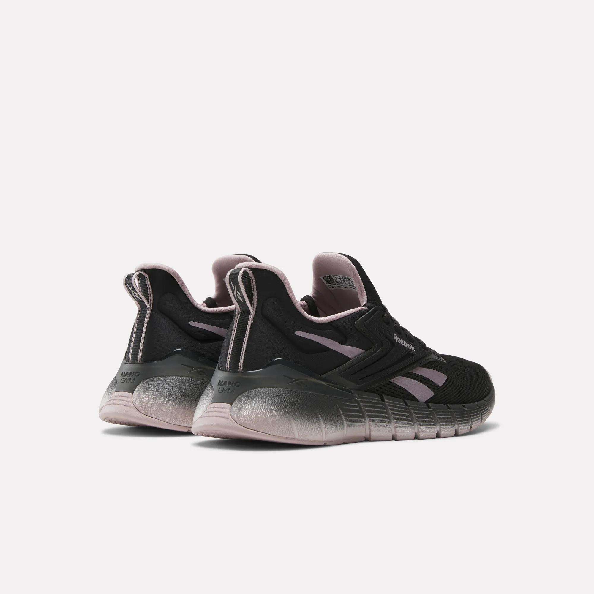 A pair of black and pink Women's Nano Gym Training Shoes by Reebok, featuring thick, textured soles, shown from the back and side against a plain light background.