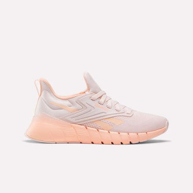 The Reebok Women's Nano Gym Training Shoes feature a light pink mesh upper, peach accents, textured sole, and heel pull tab—perfect cross-training shoes shown against a plain white background.