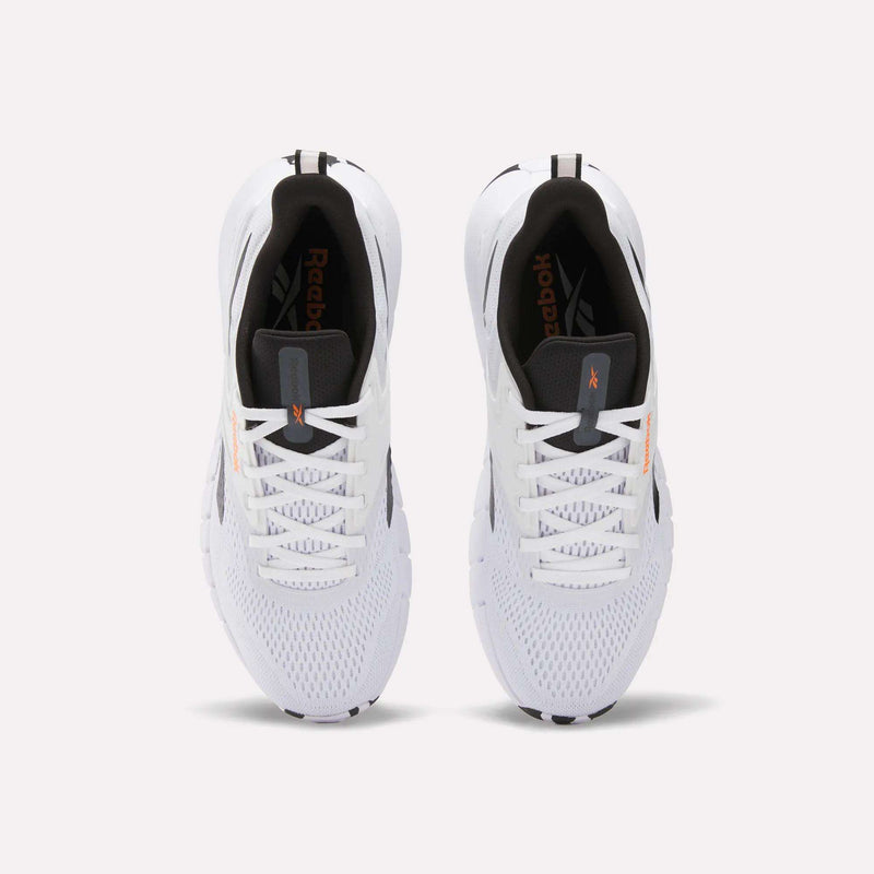Top view of a pair of Reebok Men's Nano Gym Training Shoes with black and orange accents, white laces, and black inner soles featuring a performance foam collar, placed side by side on a plain light background.