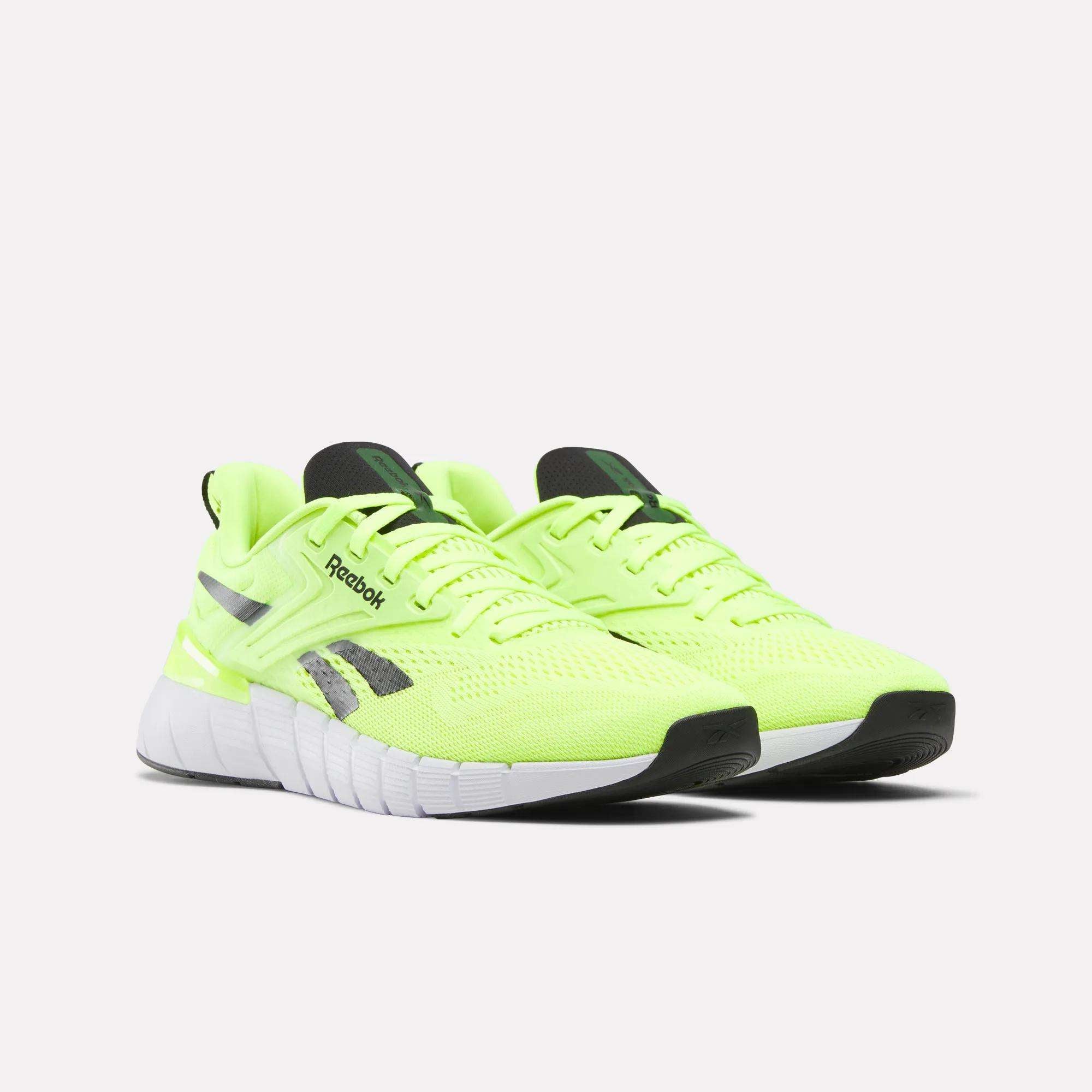 A pair of Reebok Men's Nano Gym Training Shoes in bright neon yellow with black and gray accents, white textured soles, and black outsoles, displayed on a plain white background.